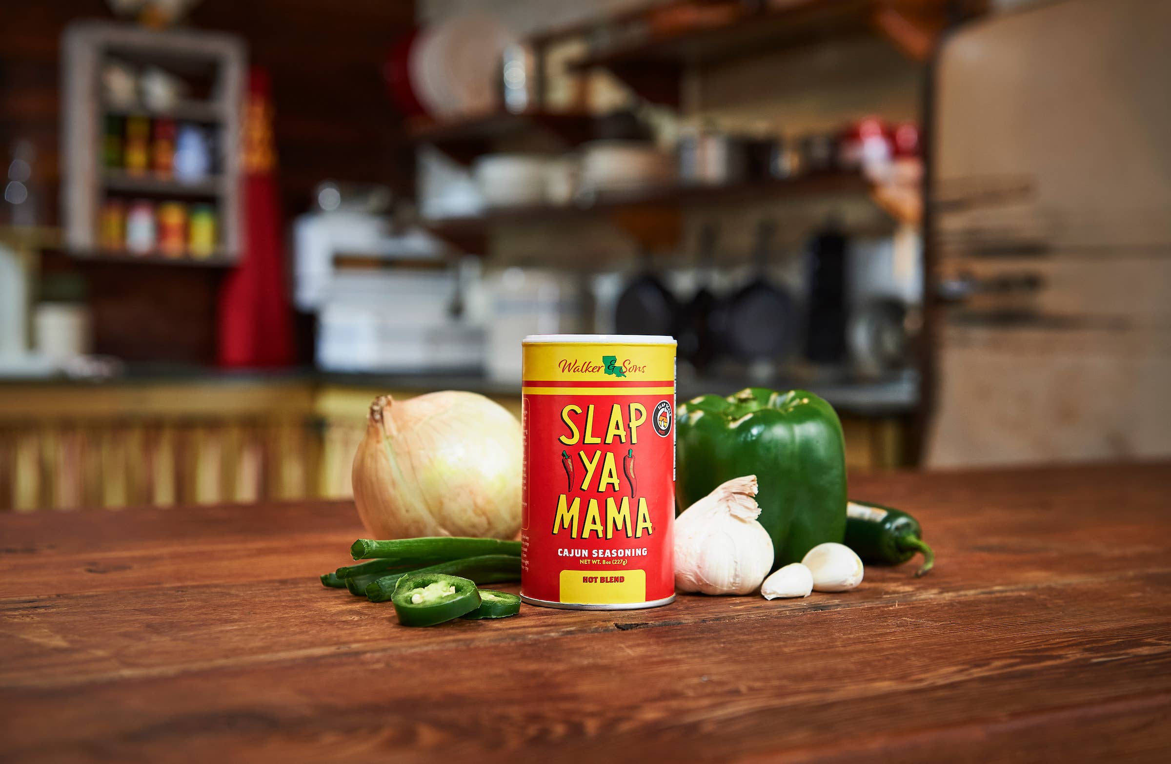 Slap Ya Mama Cajun seasoning can with onion, green pepper, garlic, and jalapenos on kitchen table