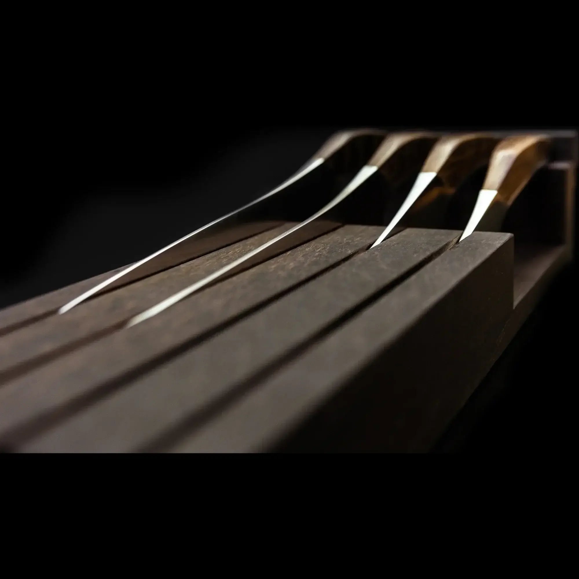 Close-up of sleek hunting knives with wooden handles in a dark wooden knife block