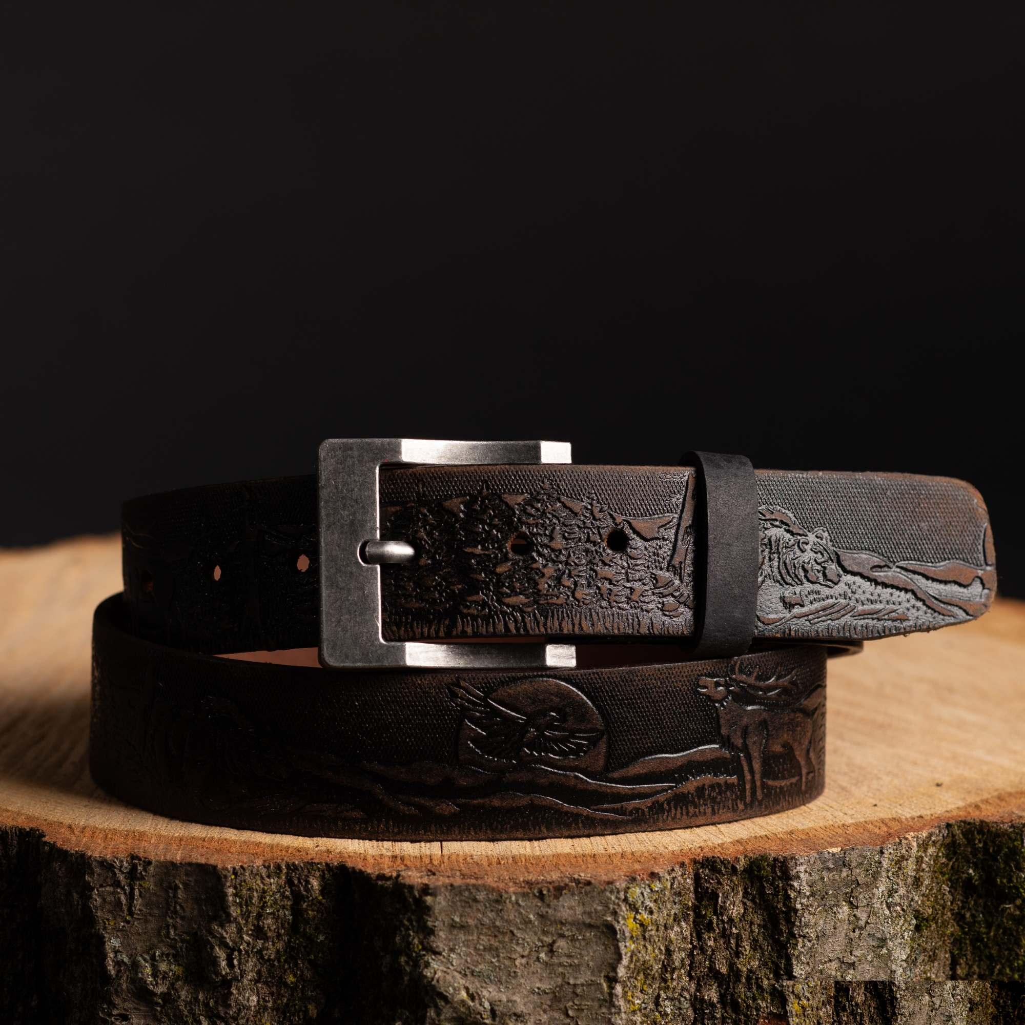 Brown leather belt with outdoor wildlife and nature engraving on wood stump, hunting gear