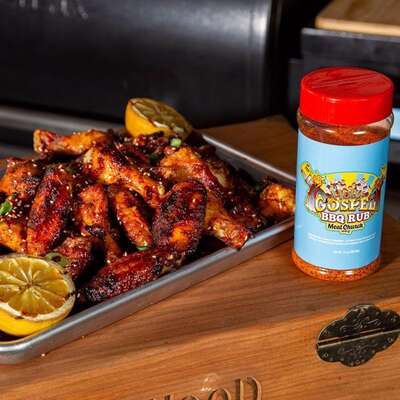 Grilled chicken wings with BBQ rub seasoning and lemon halves on a tray, barbecue setting