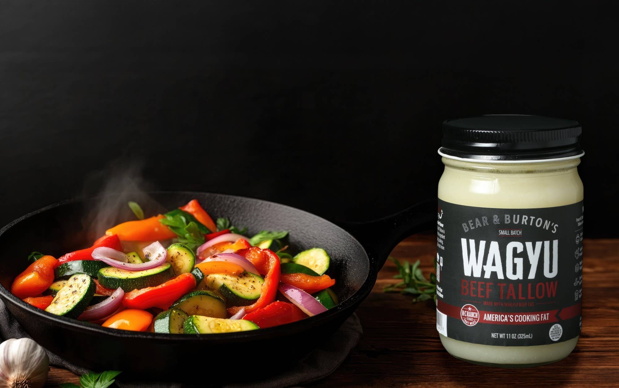 Cast iron skillet with sautéed vegetables next to a jar of Wagyu beef tallow cooking fat
