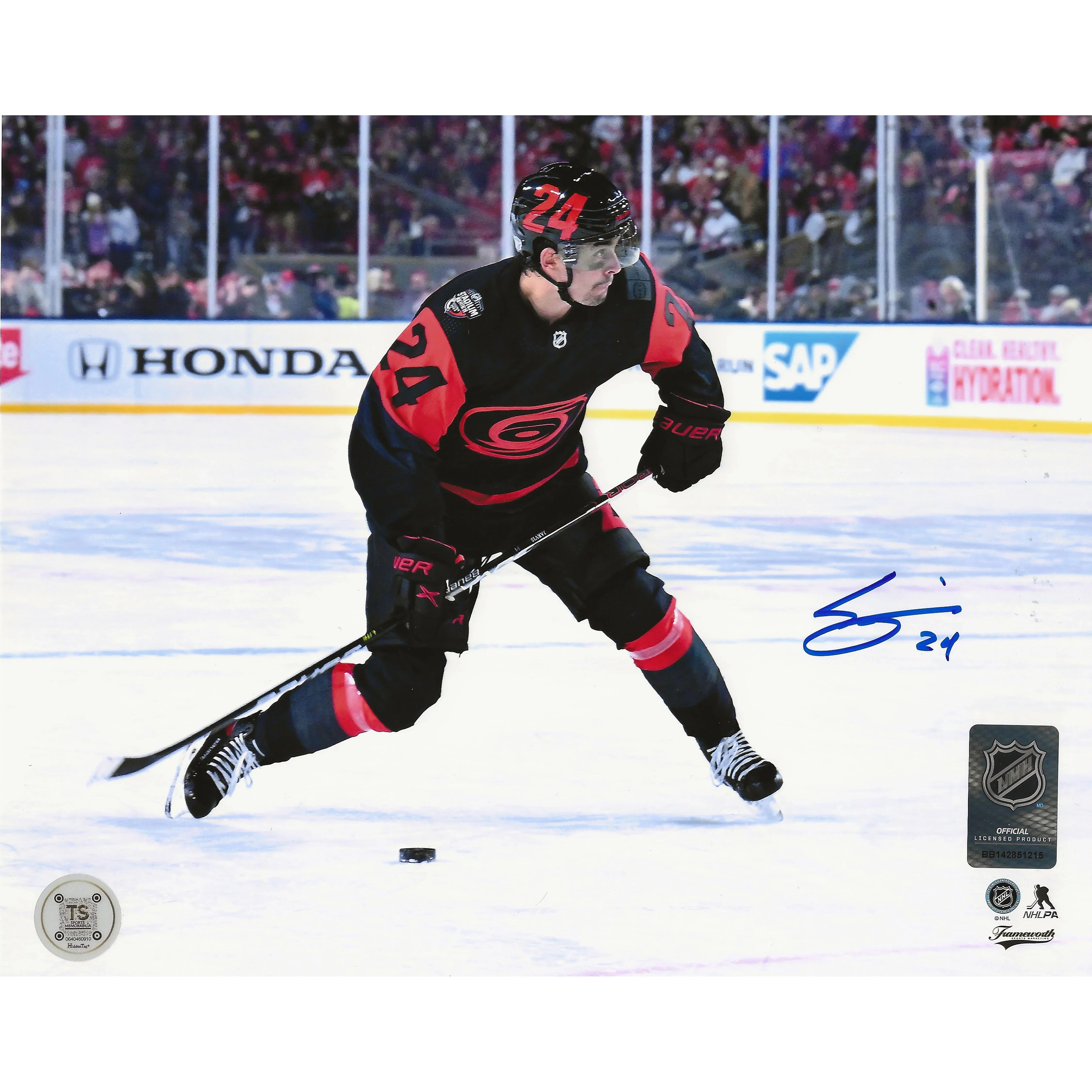 Hockey player in black and red uniform with number 24 skating on ice during game