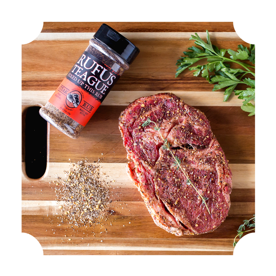 Seasoned steak with spice rub and herbs on a wooden cutting board, grilling ingredients