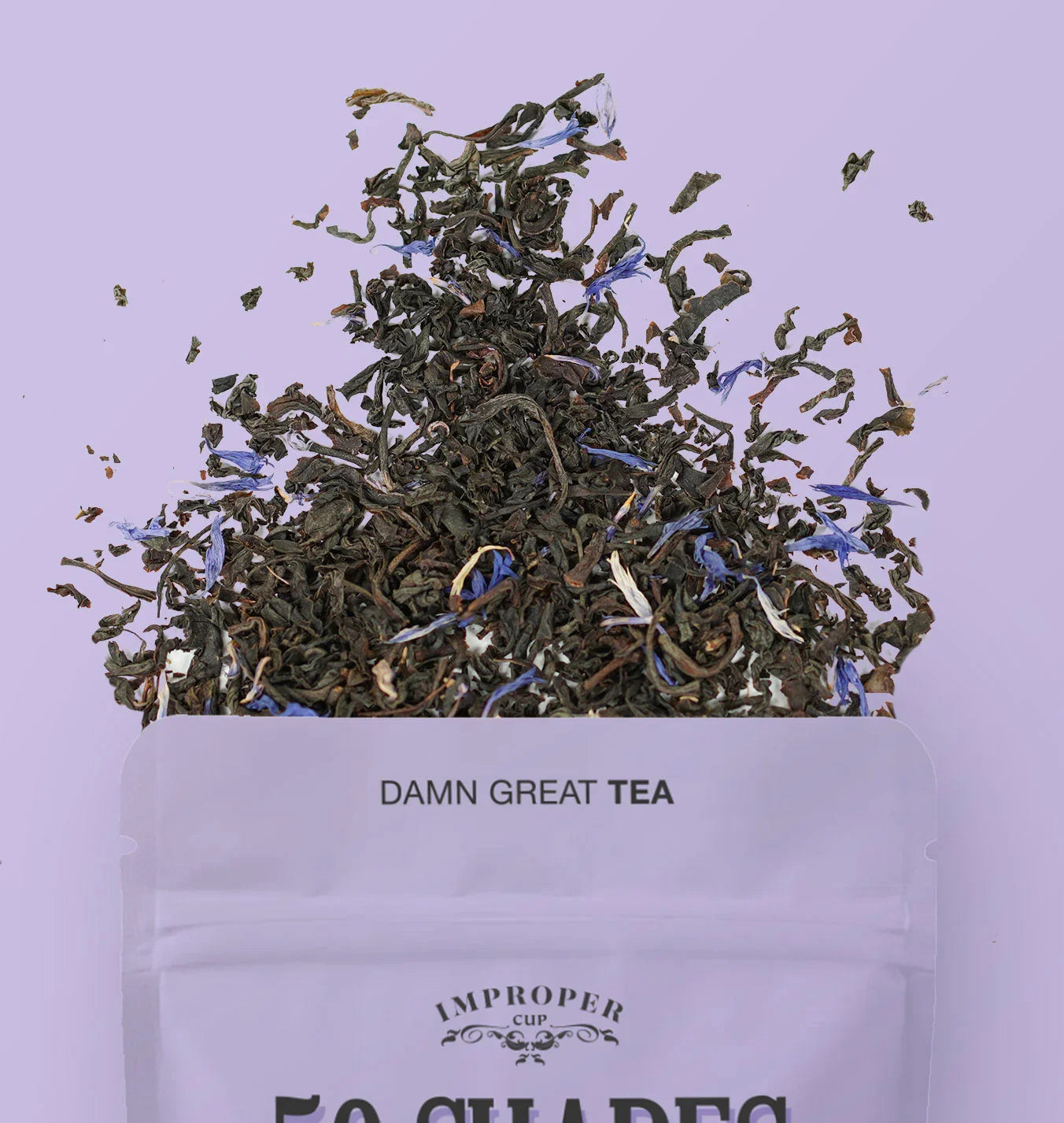 Loose leaf earl grey tea with blue petals spilling from a pouch against a light purple background
