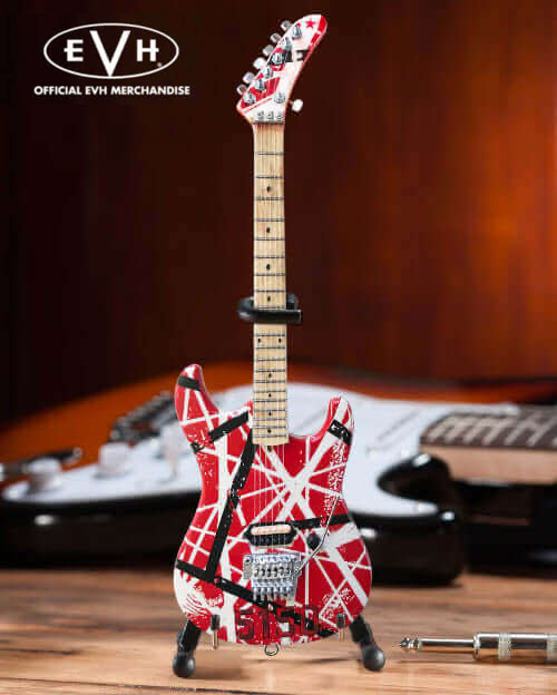 Miniature red and white striped electric guitar with stand, EVH logo, pro shop gear background.