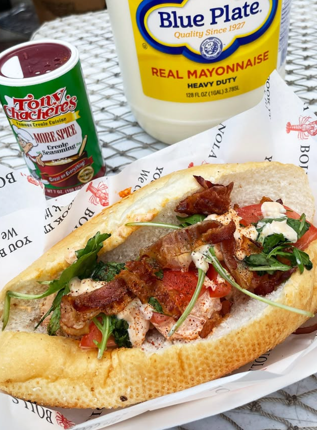 Bacon, lettuce, tomato sandwich on sub roll with mayo and Creole seasoning on a table