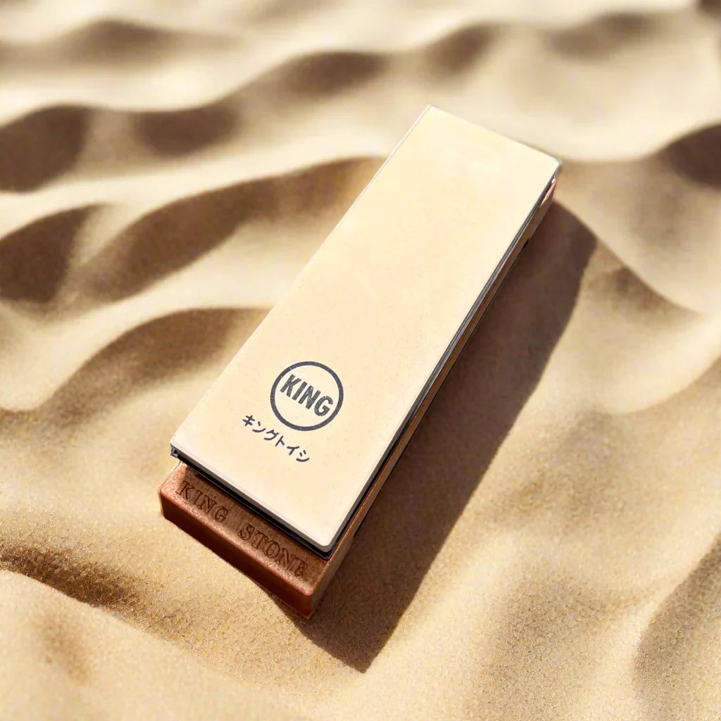 King sharpening stone on sand, ideal for camping and hunting knife maintenance