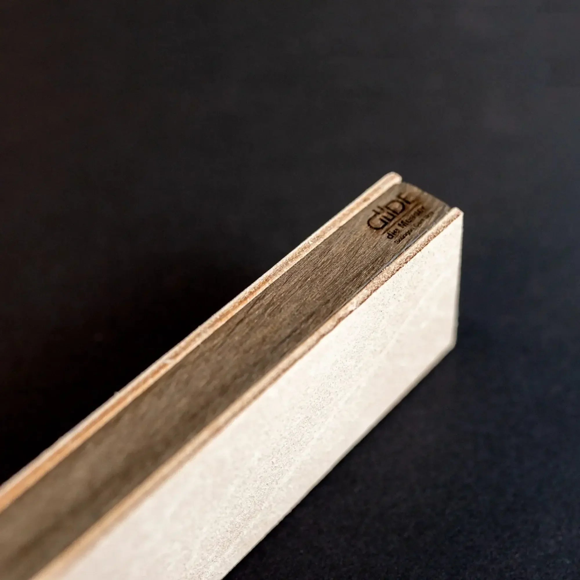 Close-up of a wooden sharpening strop block with leather surface on dark background