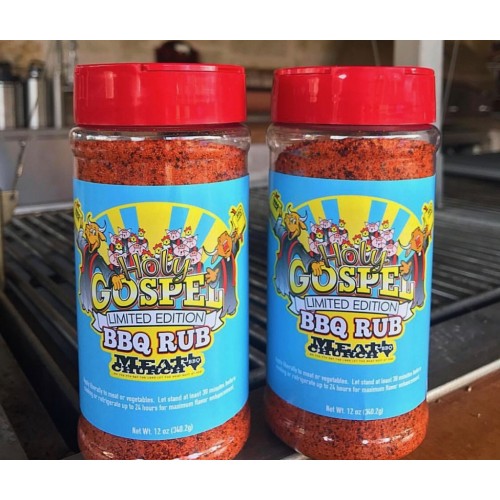Two jars of Holy Gospel Limited Edition BBQ Rub with red lids on an outdoor grill surface.