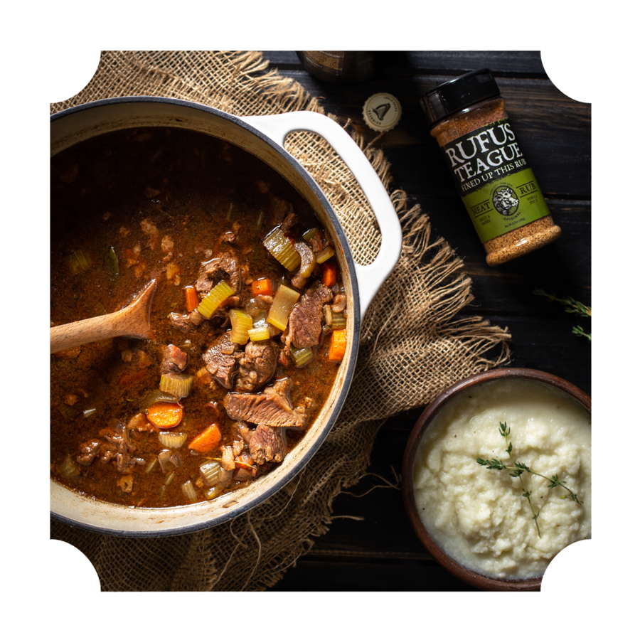 Hearty beef and vegetable stew in white pot with mashed potatoes and Rufus Teague seasoning