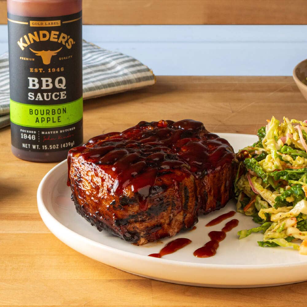 Grilled steak with bourbon apple BBQ sauce and coleslaw on a plate, BBQ sauce bottle nearby