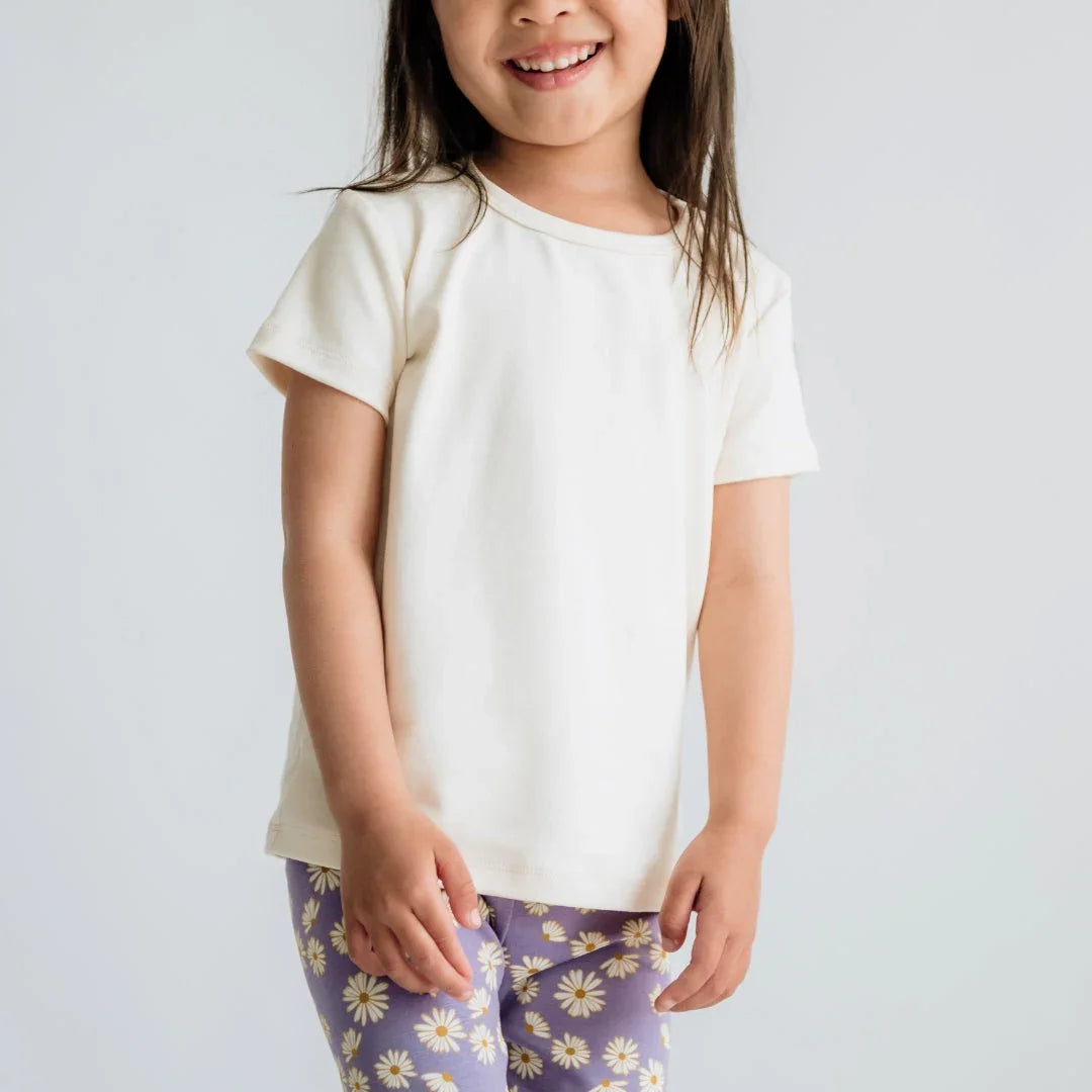 Smiling girl in white short sleeve t-shirt and purple daisy print leggings