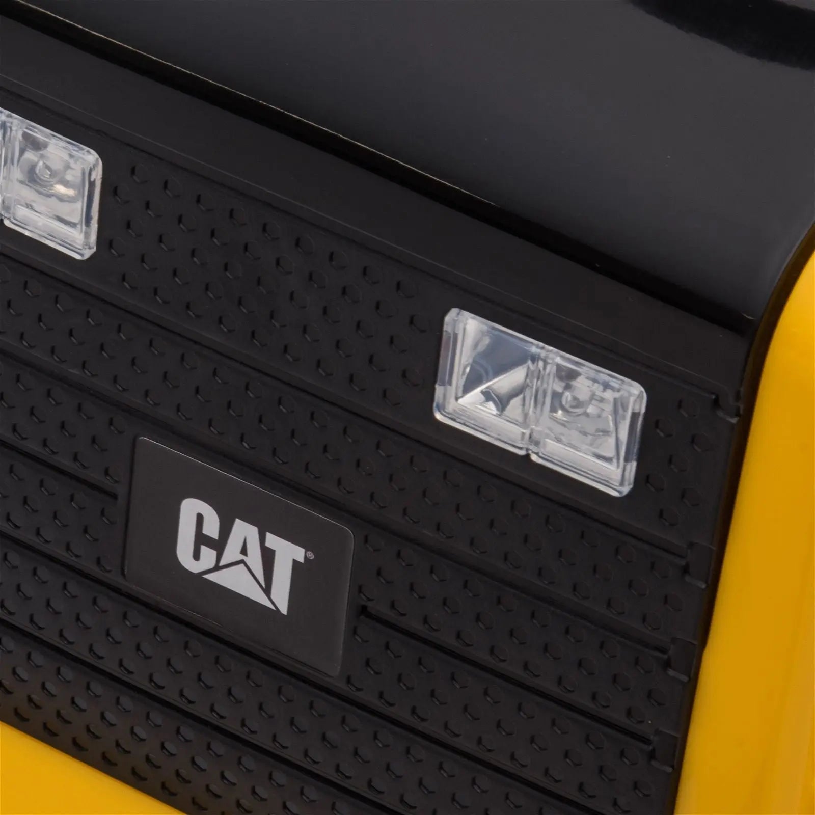 Close-up of toy dump truck front grill with headlights and CAT logo, black and yellow