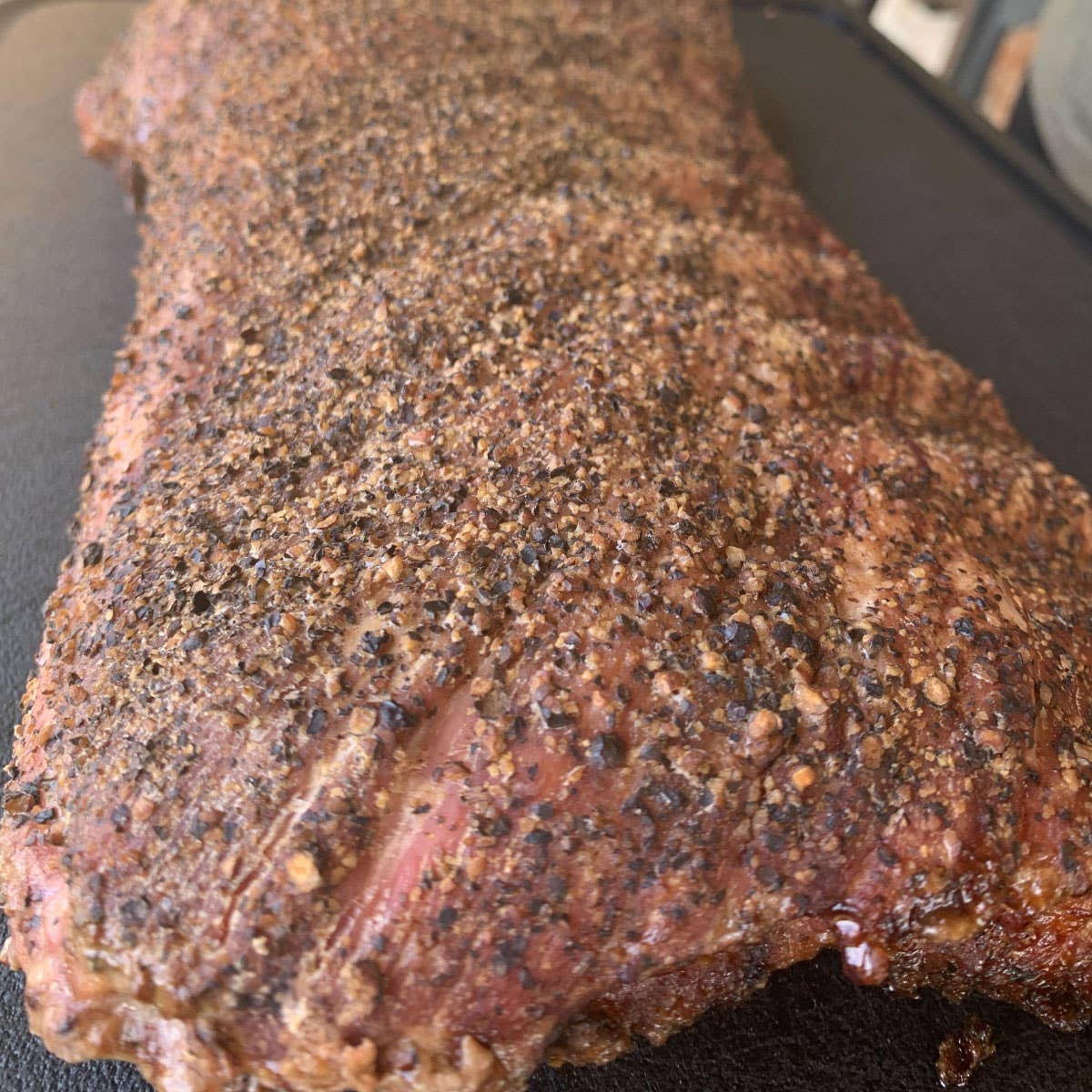 Close-up of seasoned smoked brisket with pepper crust, ideal for camping and outdoor cooking