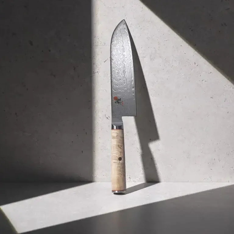 Japanese chef knife with Damascus steel blade and wooden handle on stone surface