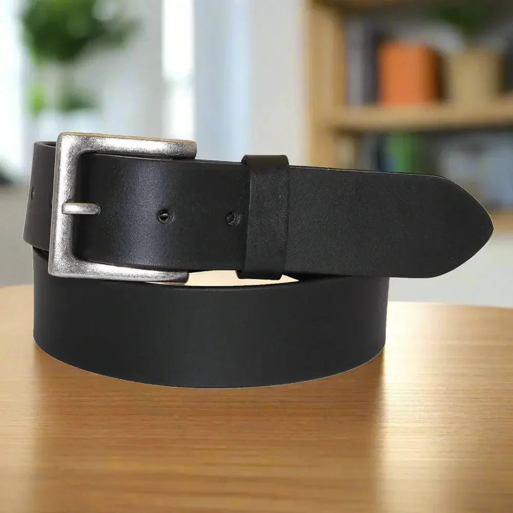 Men's black solid leather belt with removable silver buckle on wooden table