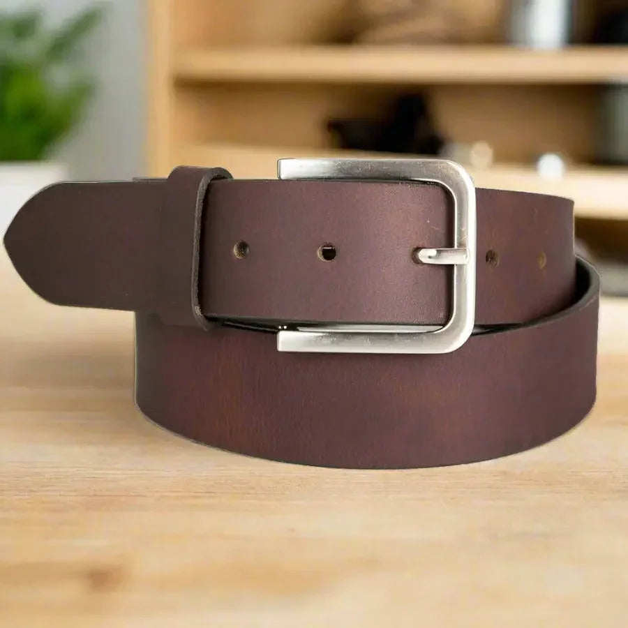 Brown men's leather belt with silver removable buckle on wooden surface
