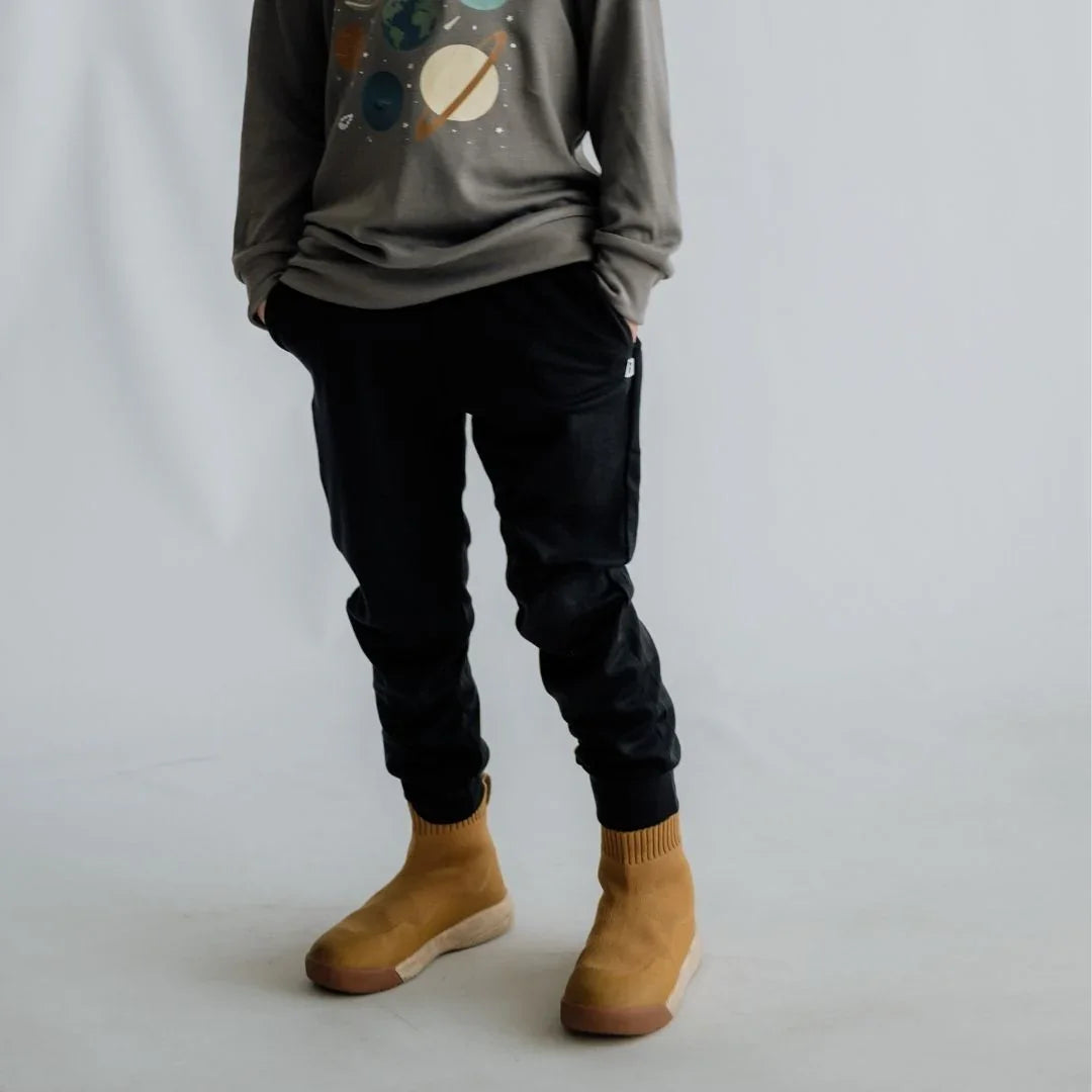 Person wearing space graphic sweatshirt, black joggers, and tan high-top shoes on white background