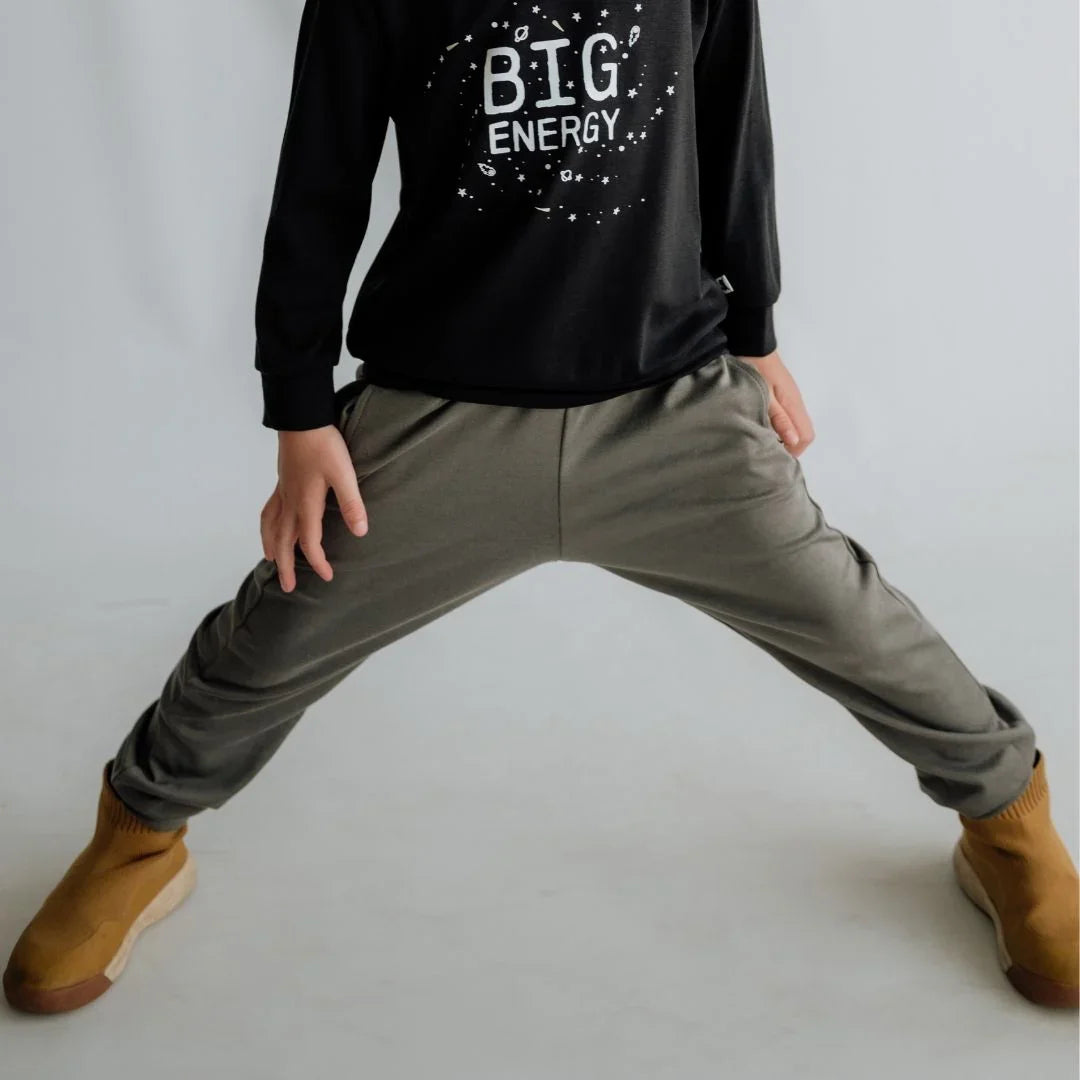 Child wearing 'Big Energy' black sweatshirt, olive joggers, and tan slip-on shoes
