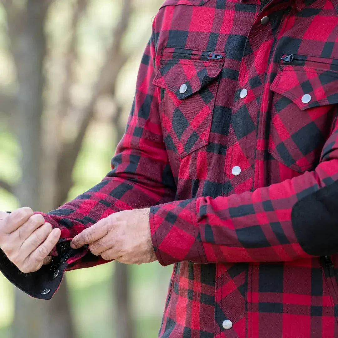 Man wearing red and black armored flannel biker shirt adjusting sleeve outdoors
