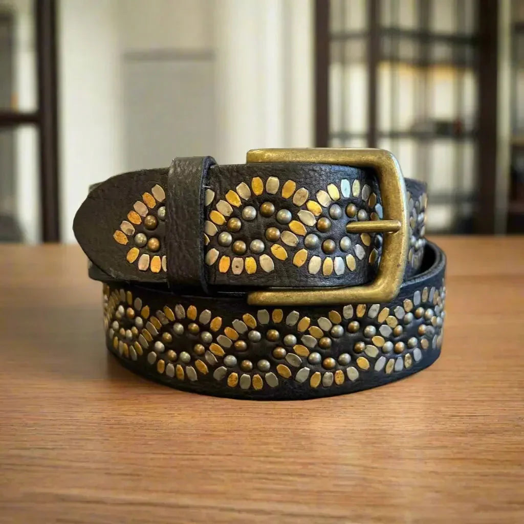 Women's full-grain leather belt with gold studs on a wooden surface