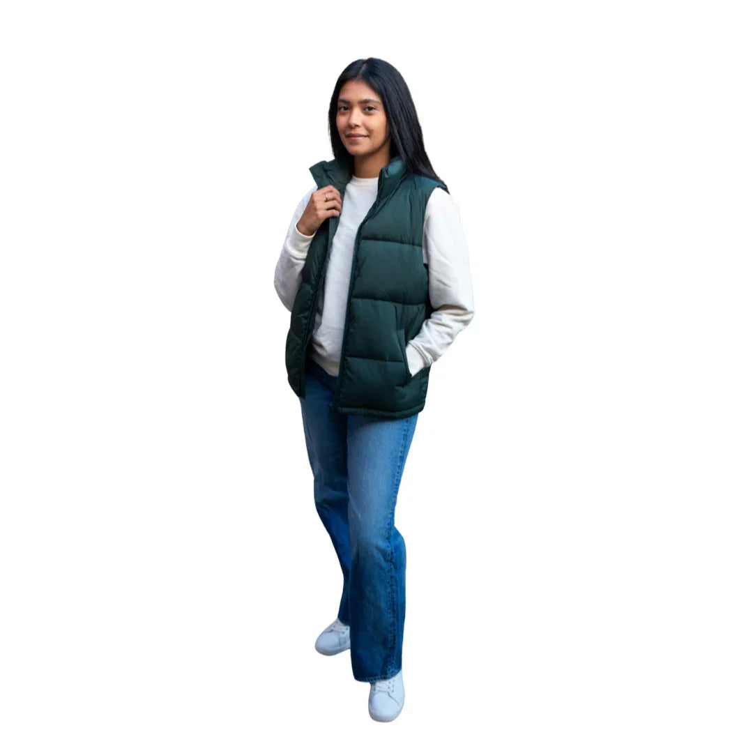 Woman wearing green puffer vest, white sweater, blue jeans, and white shoes on white background