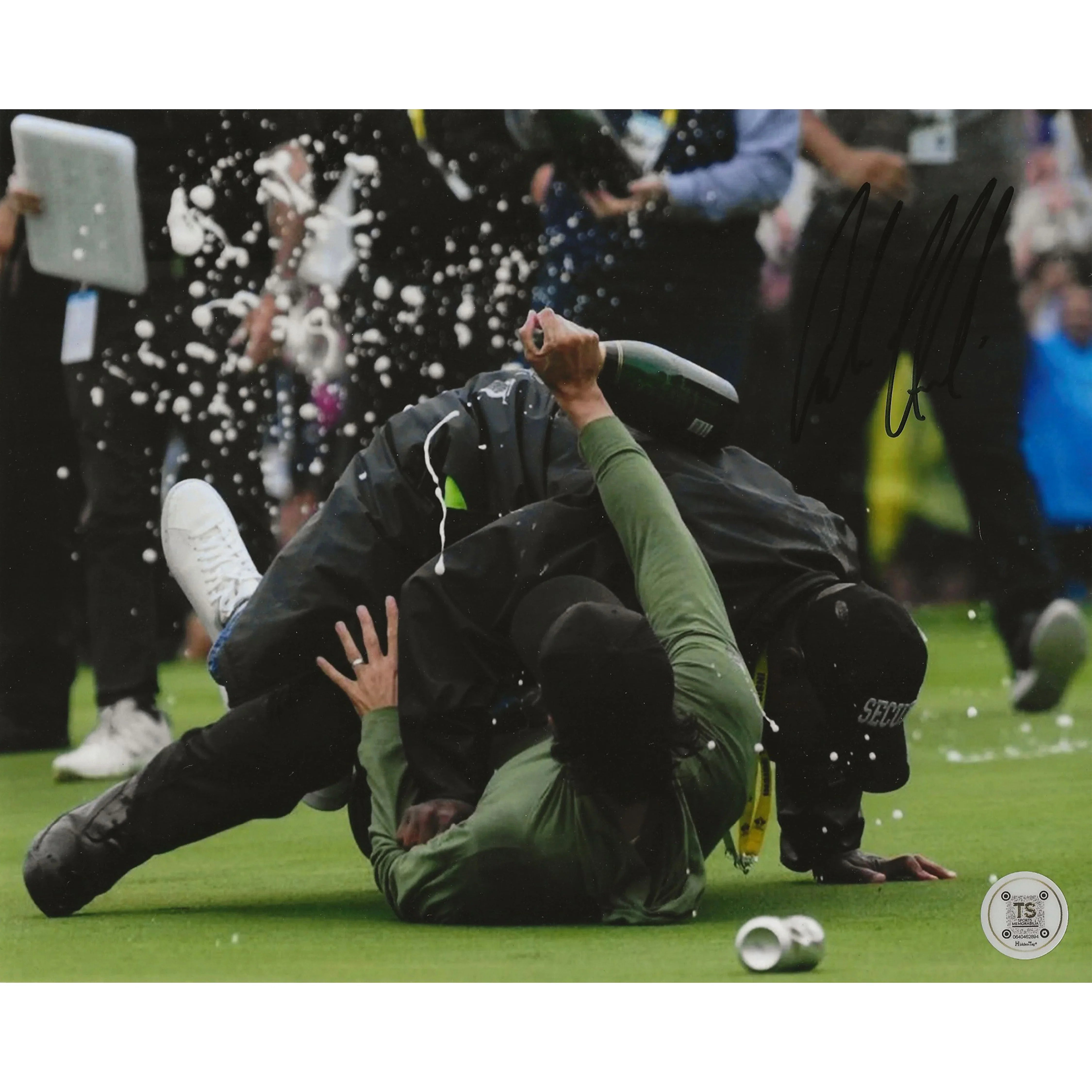 Security tackle on golf course with champagne spraying, crowd in background, sports action