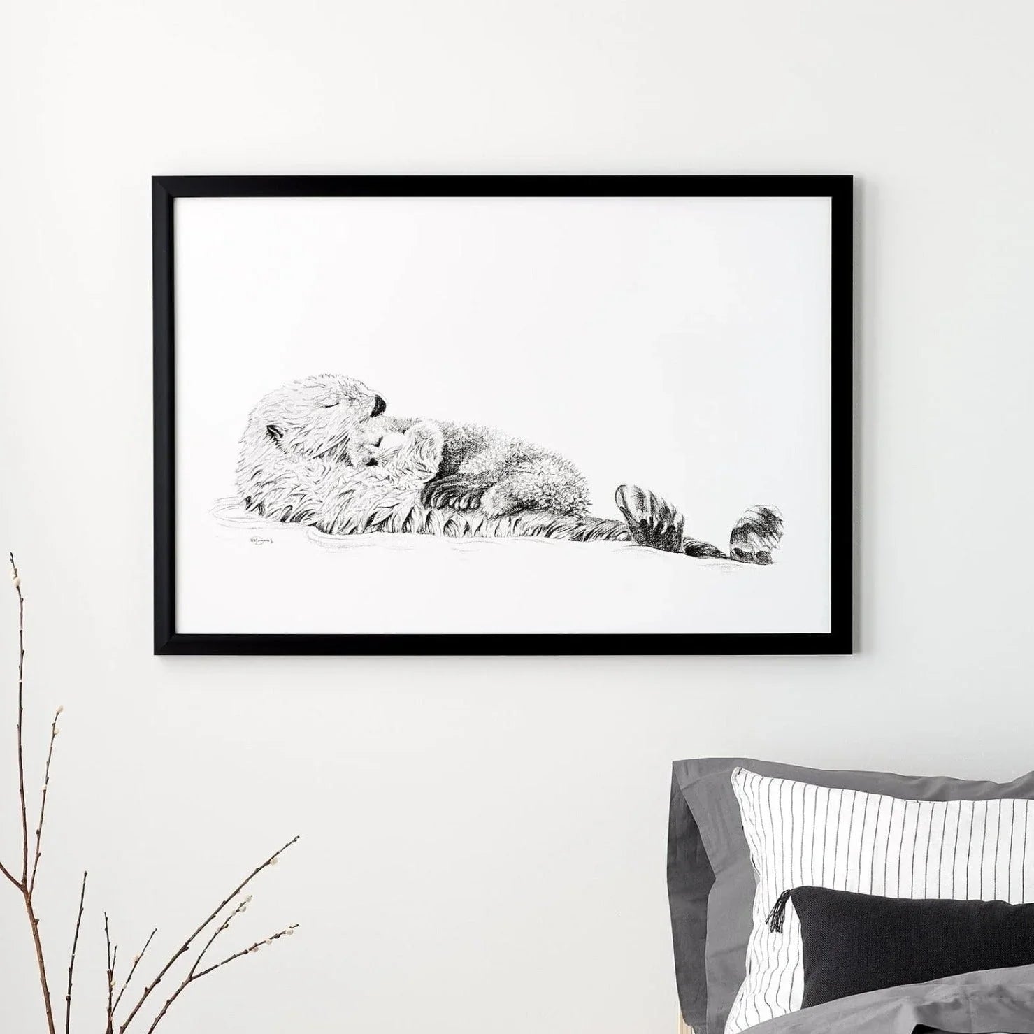 Black and white framed sea otter and cub art print on a modern bedroom wall