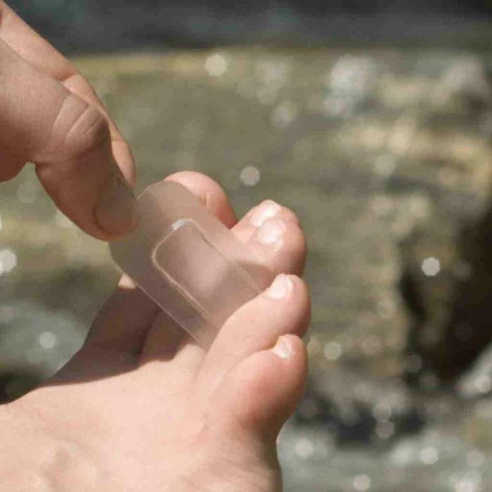 Applying GlacierGel blister bandage to toe outdoors, foot care for hiking or sports injuries