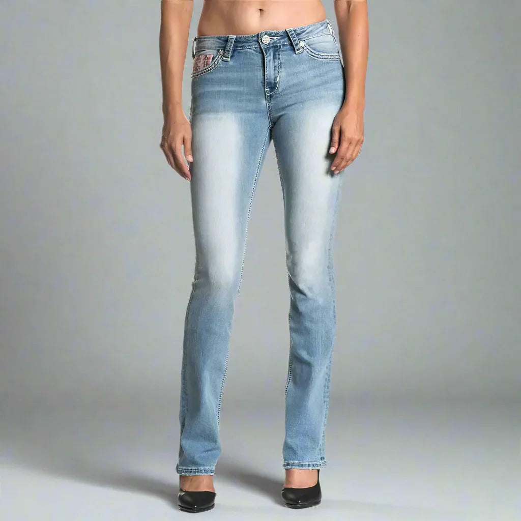 Woman modeling light wash Affliction Jade Aries Ember jeans with faded front detail
