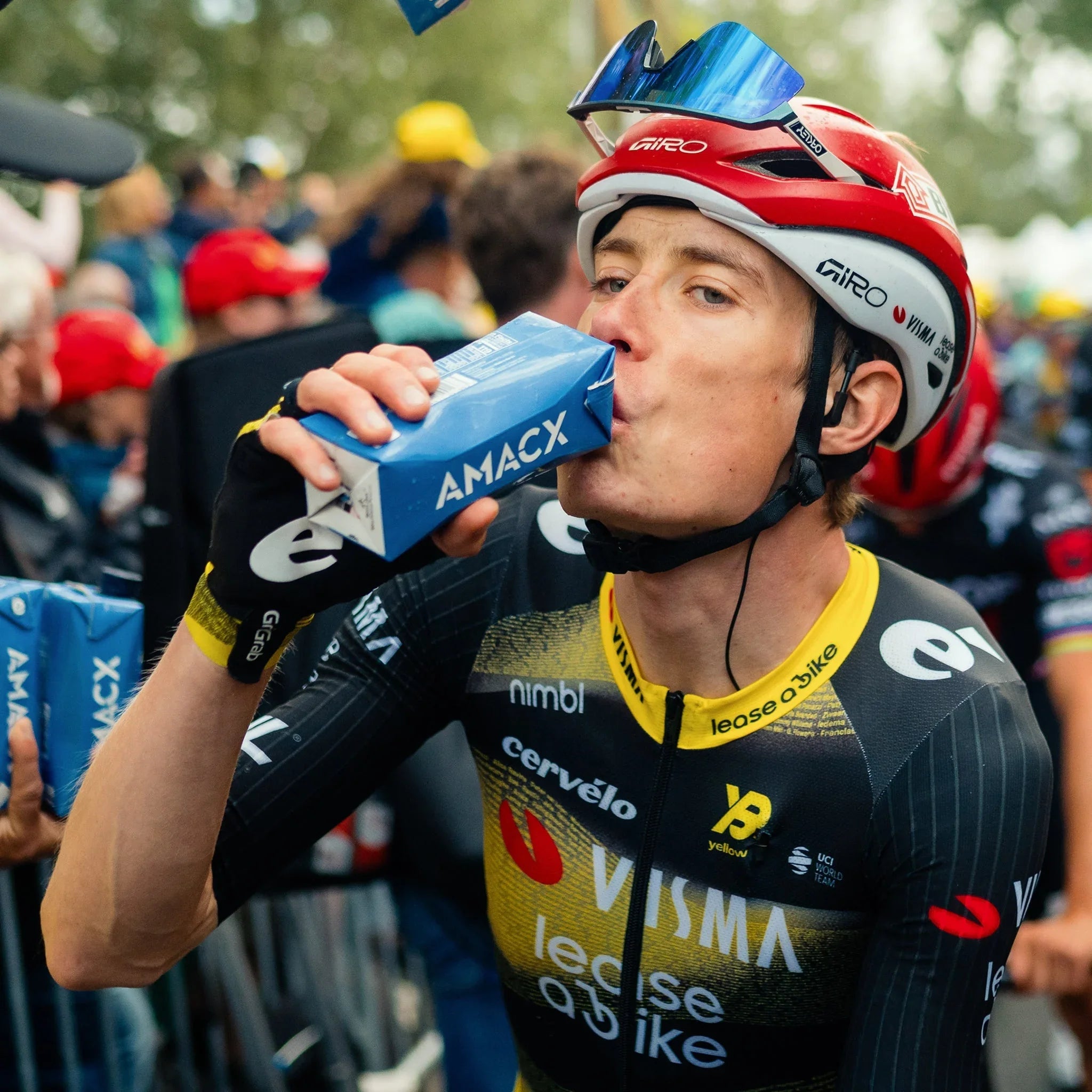 Cyclist in Team Visma jersey drinks AMACX cherry juice after race, wearing helmet and sunglasses
