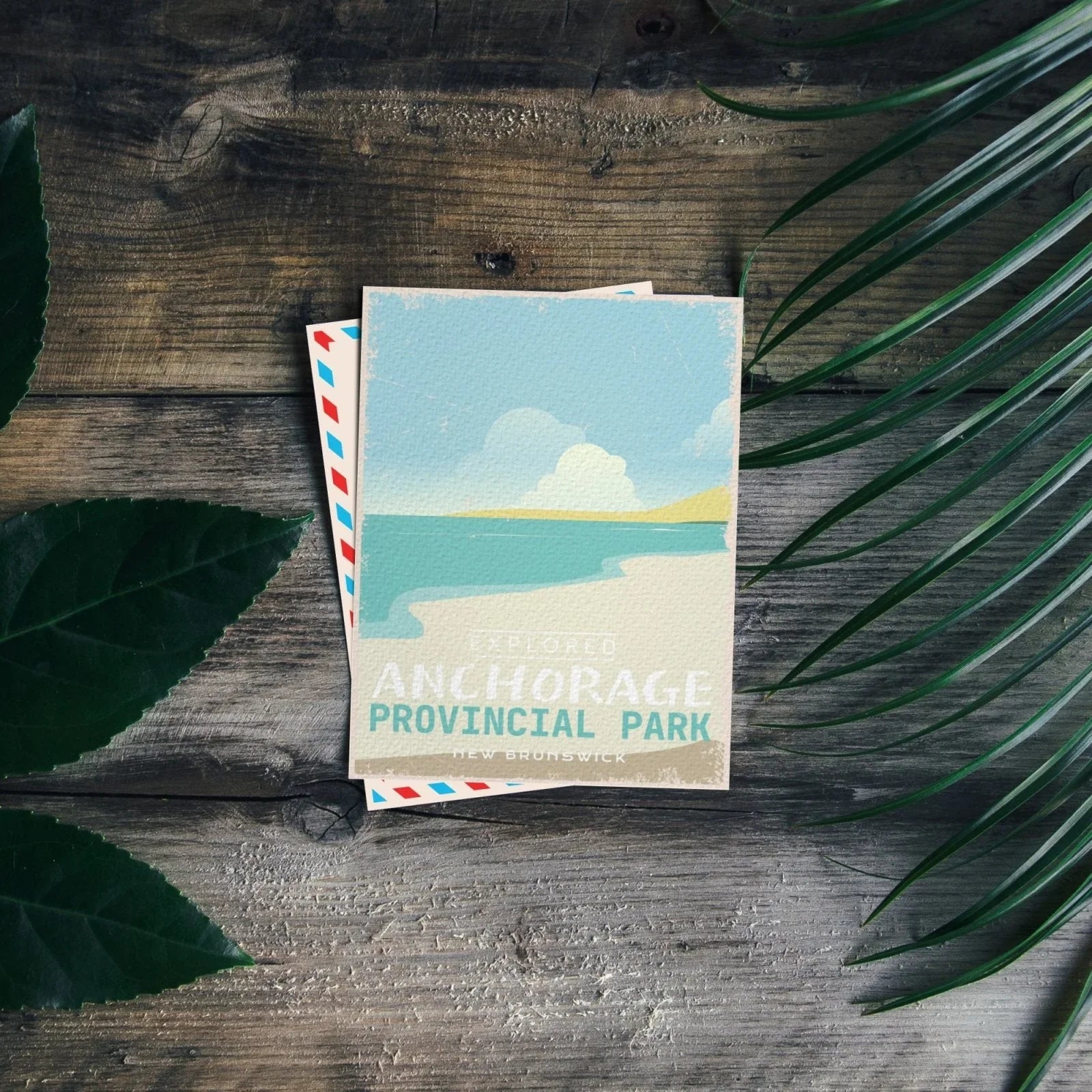 Anchorage Provincial Park New Brunswick postcard on rustic wood with green leaves