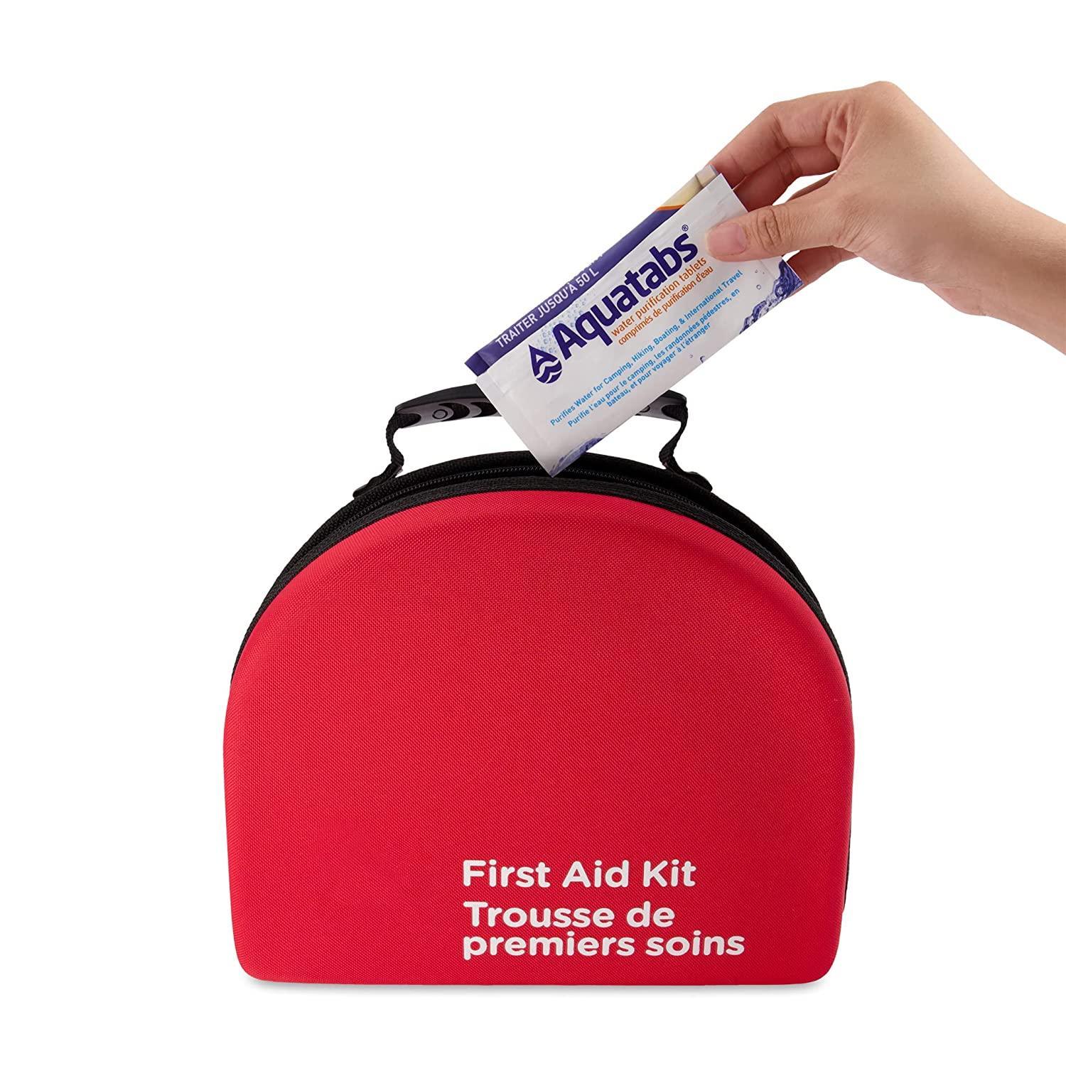 Hand placing Aquatabs water purification tablets into red first aid kit bag