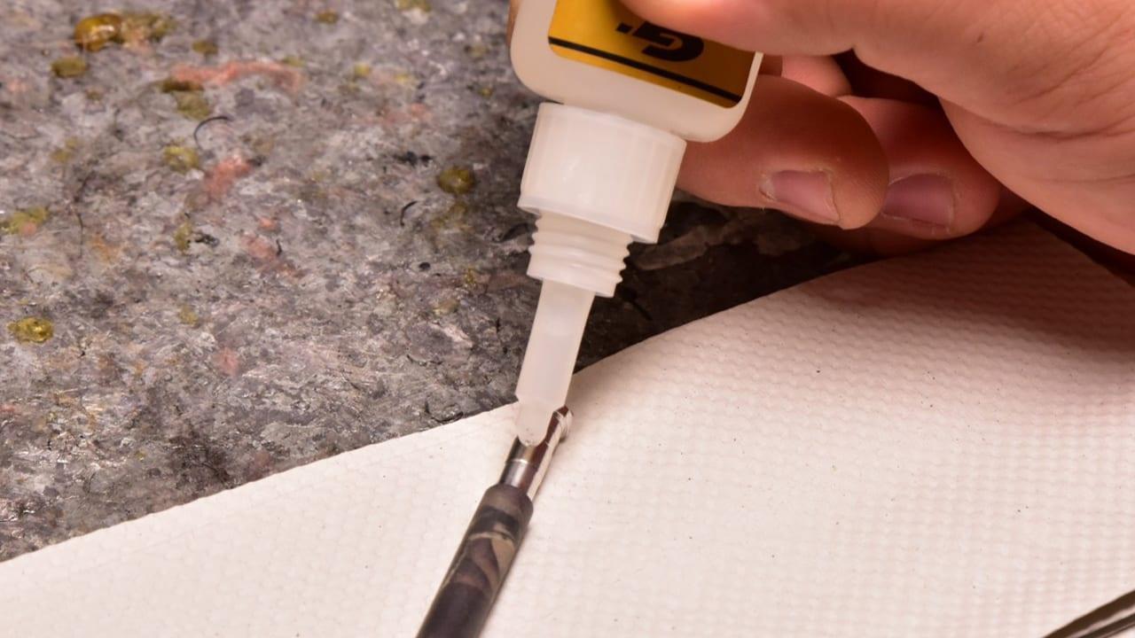 Hand applying glue to arrow insert on textured surface for Leapfrog outdoor arrow installation