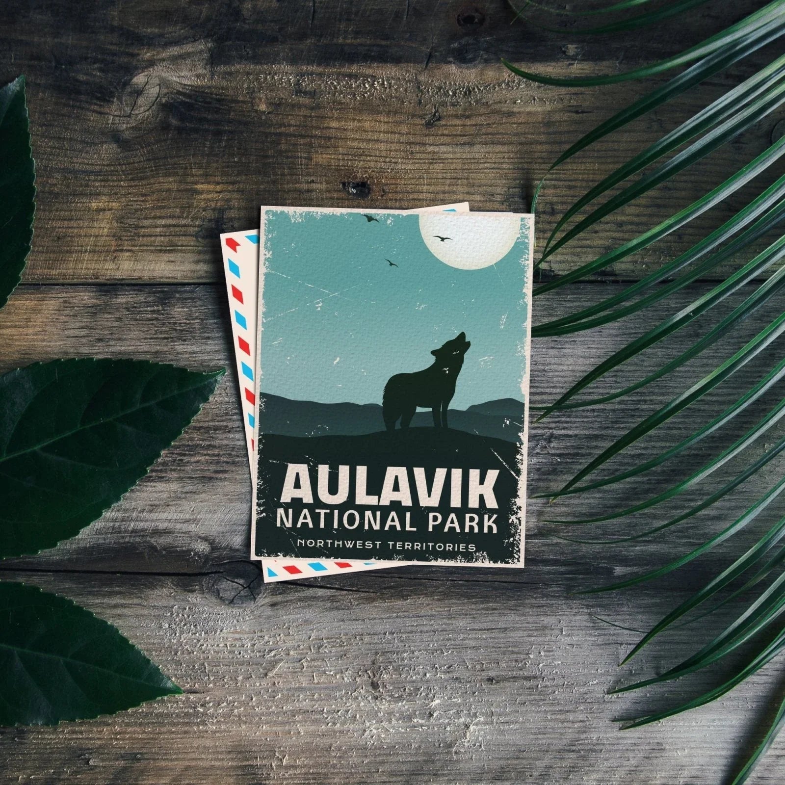 Aulavik National Park postcard with wolf silhouette on rustic wood and green leaves