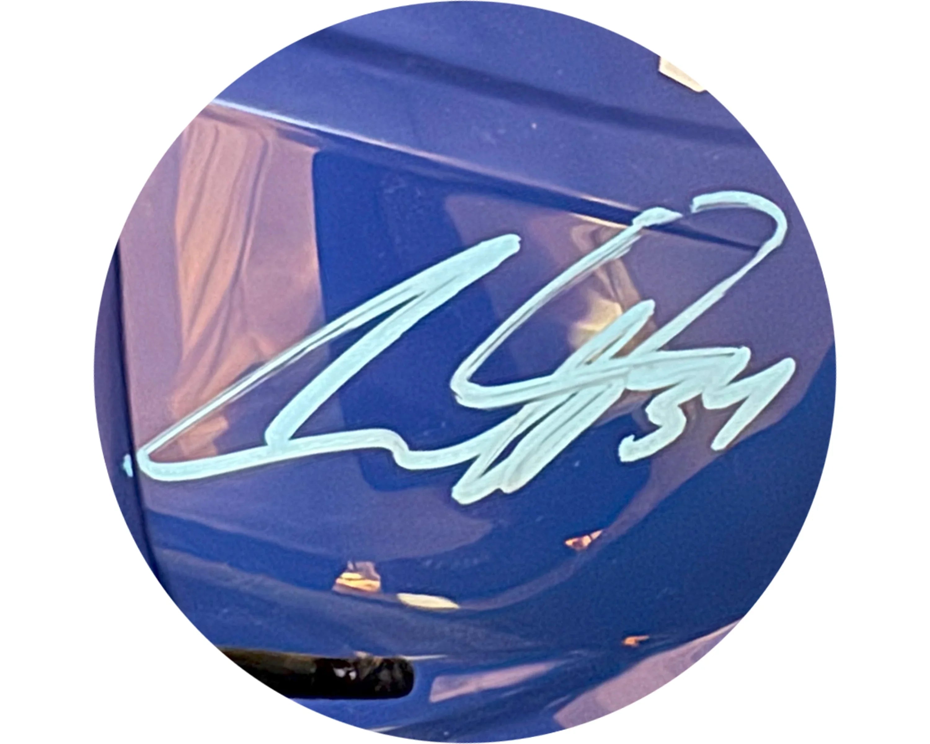 Silver autograph on glossy blue surface, close-up, with reflective highlights, collectible item