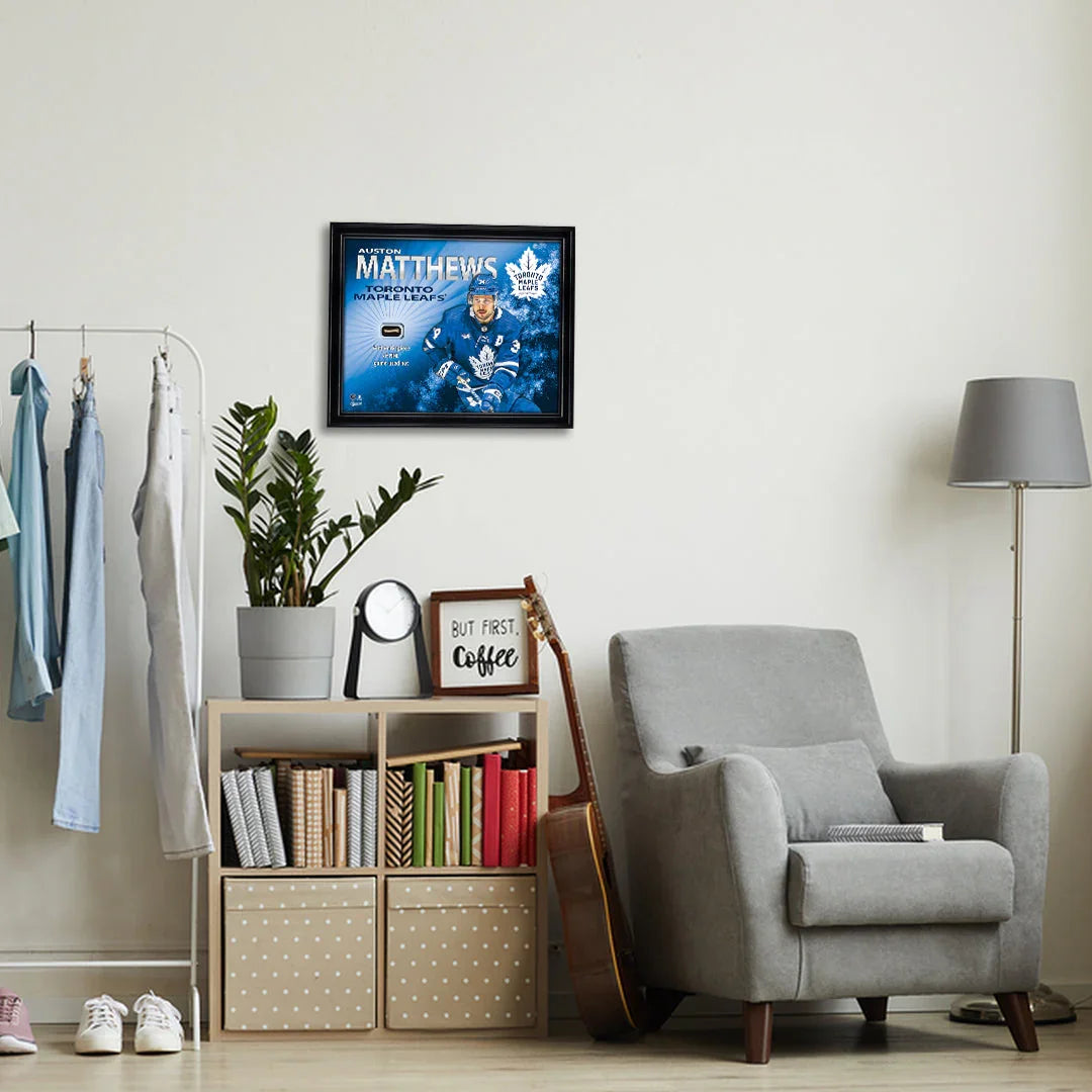 Modern living room with gray armchair, bookshelf, and framed Toronto Maple Leafs hockey art on wall