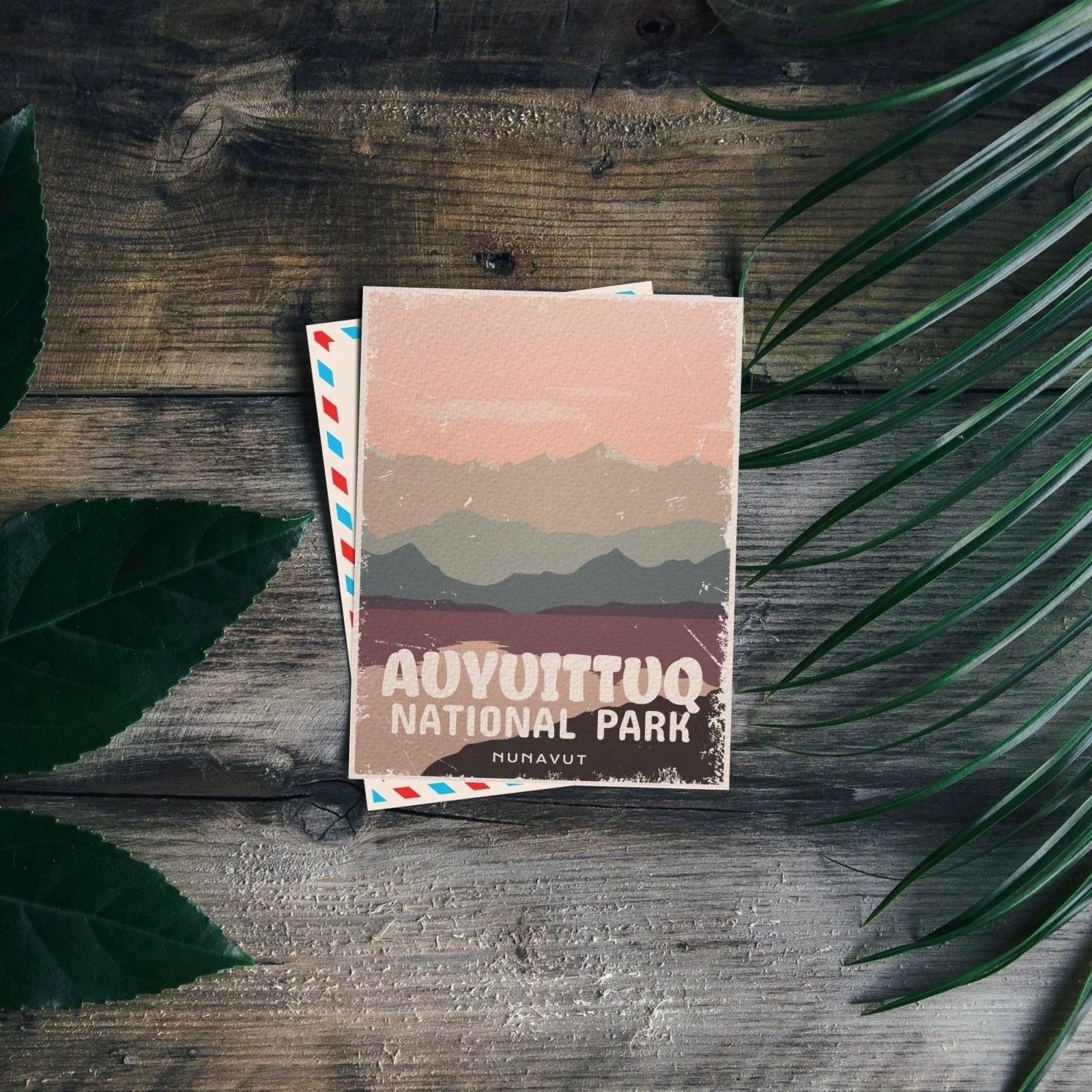 Auyuittuq National Park postcard with stylized mountain landscape on rustic wooden table