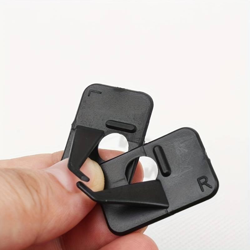 Black stick-on recurve arrow rests labeled L and R, held between fingers on white background