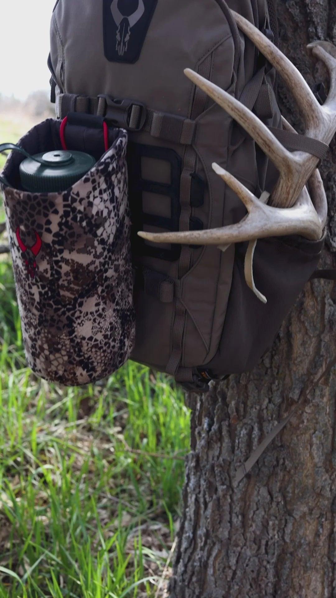 Badlands ATX-25 frame pack with camo pouch and deer antlers hanging on a tree outdoors