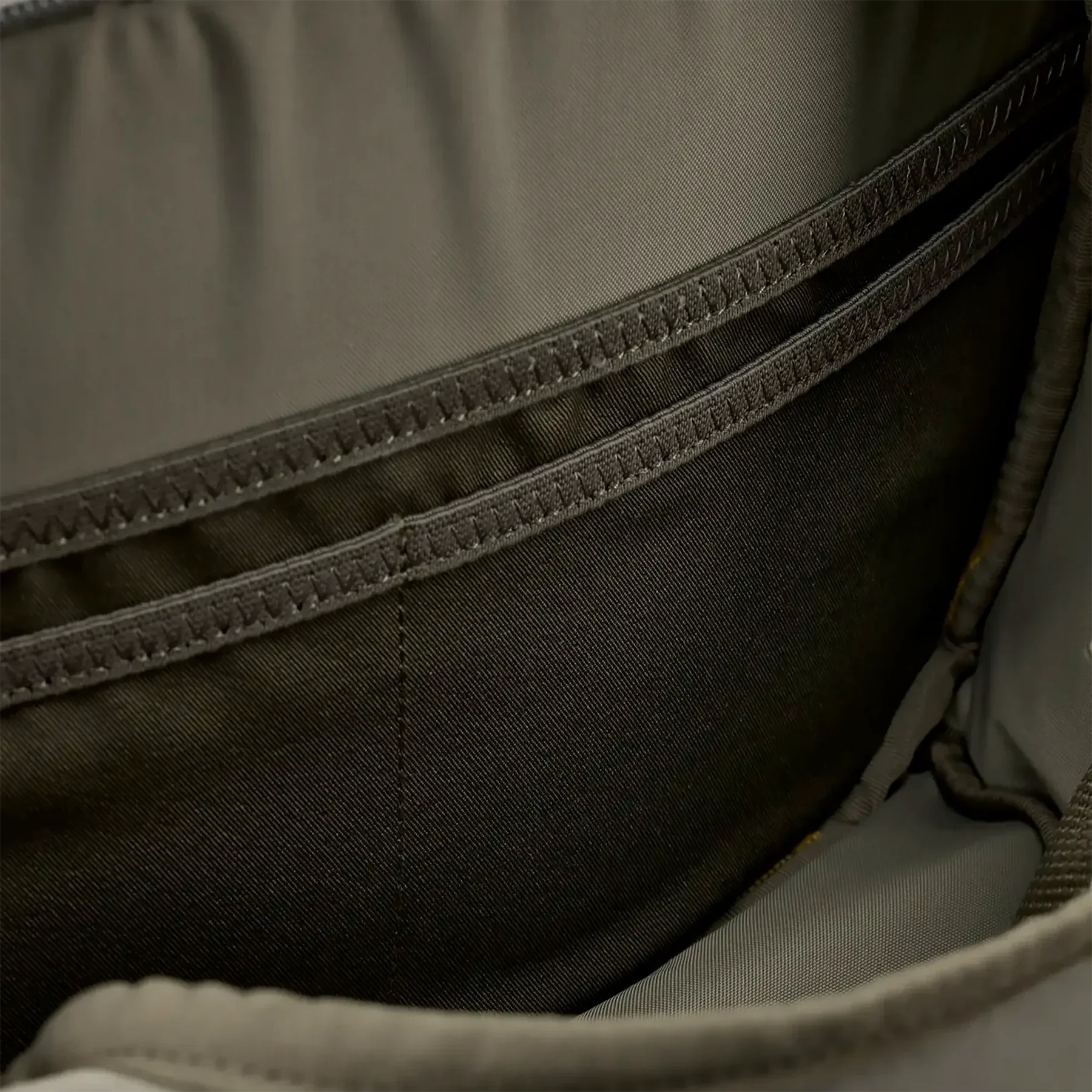 Close-up of interior pocket stitching in khaki fanny pack bag compartment