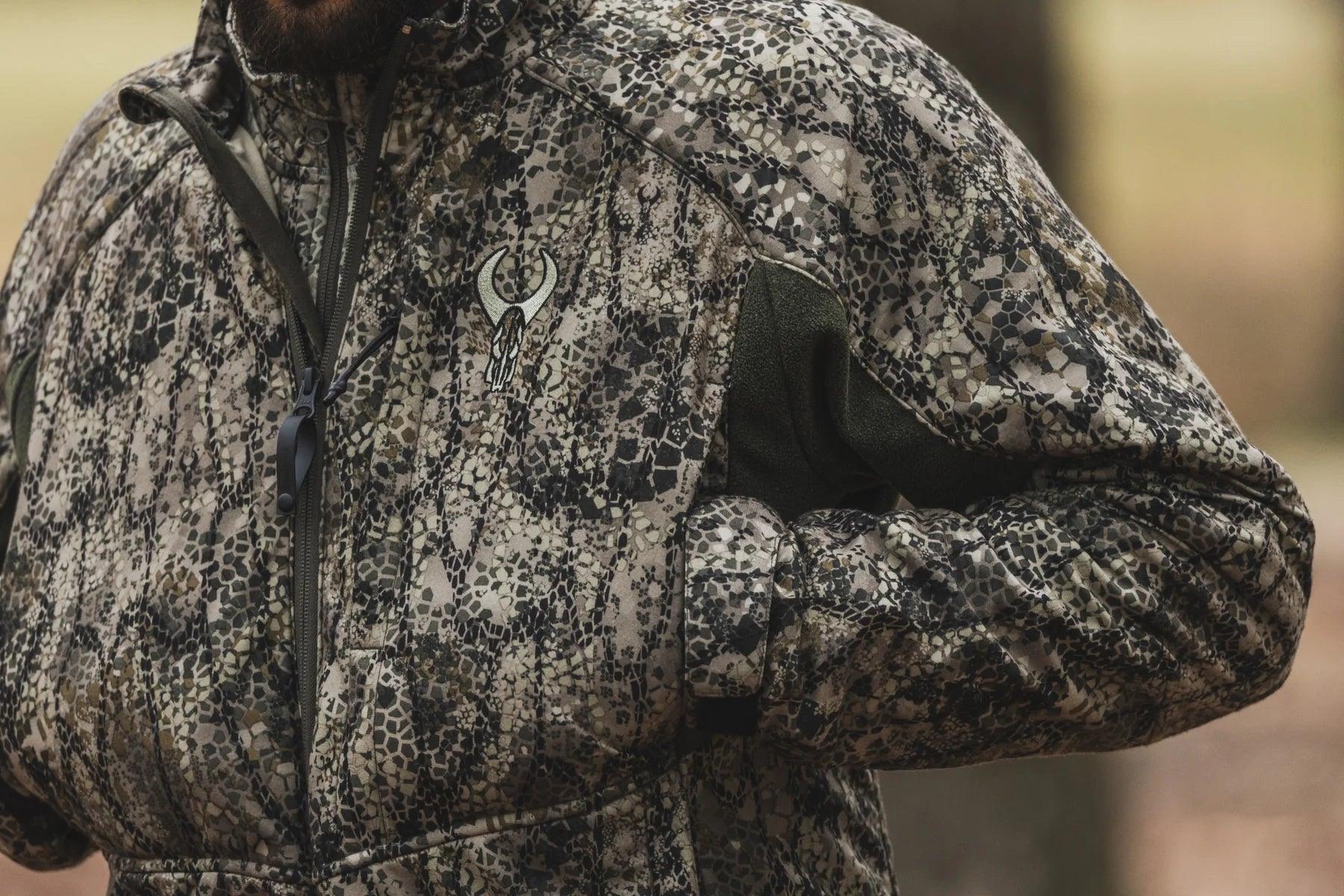 Close-up of camouflage hunting jacket with embroidered skull logo, outdoors