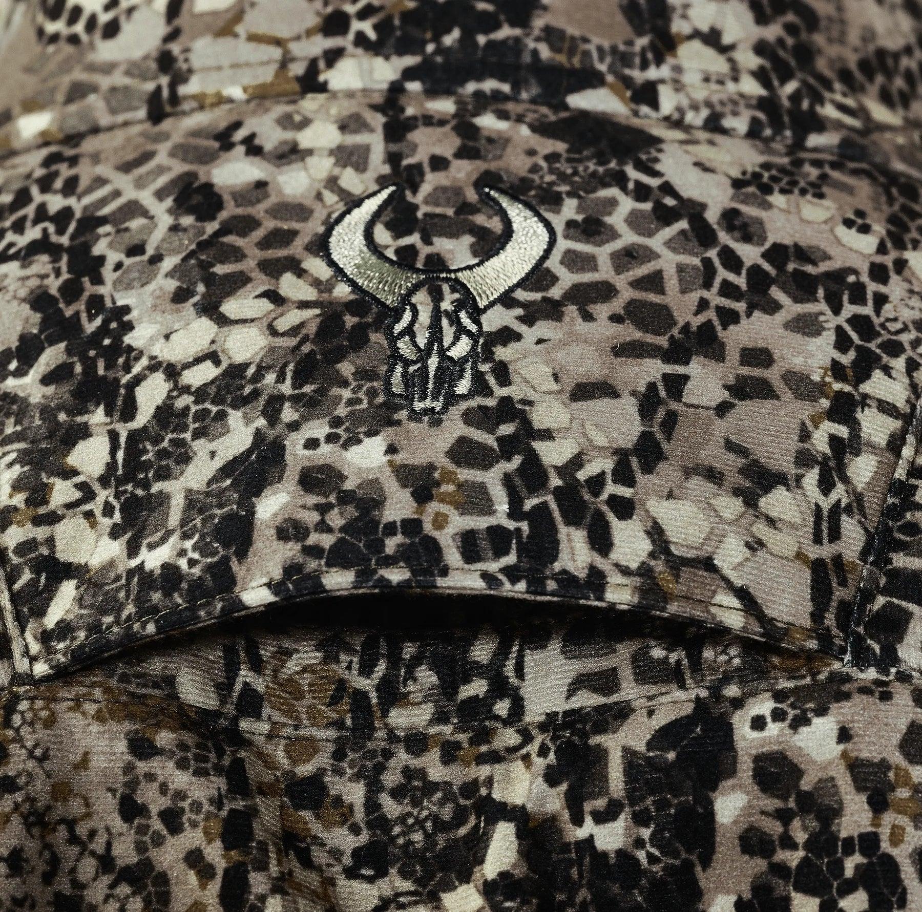 Camo pattern fabric with embroidered bull skull logo, outdoor hunting clothing detail