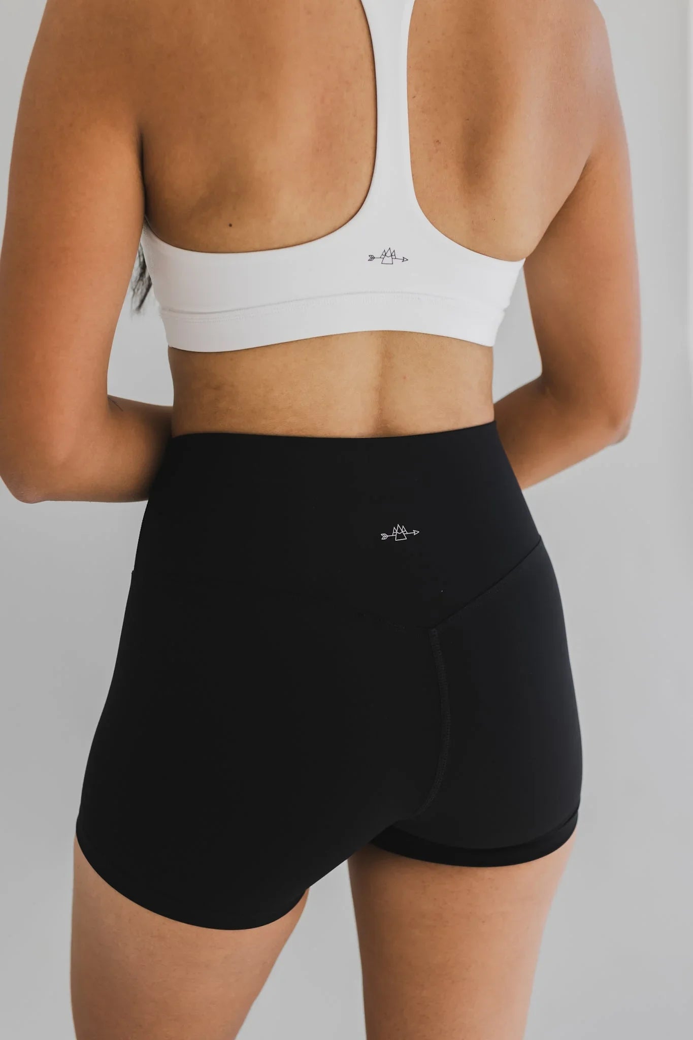 Woman wearing black high-waisted athletic shorts and a white racerback sports bra