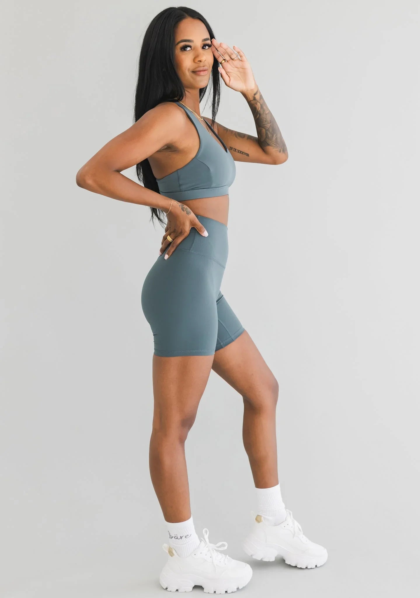 Woman in blue sports bra and high-waisted biker shorts posing in athletic wear studio shot