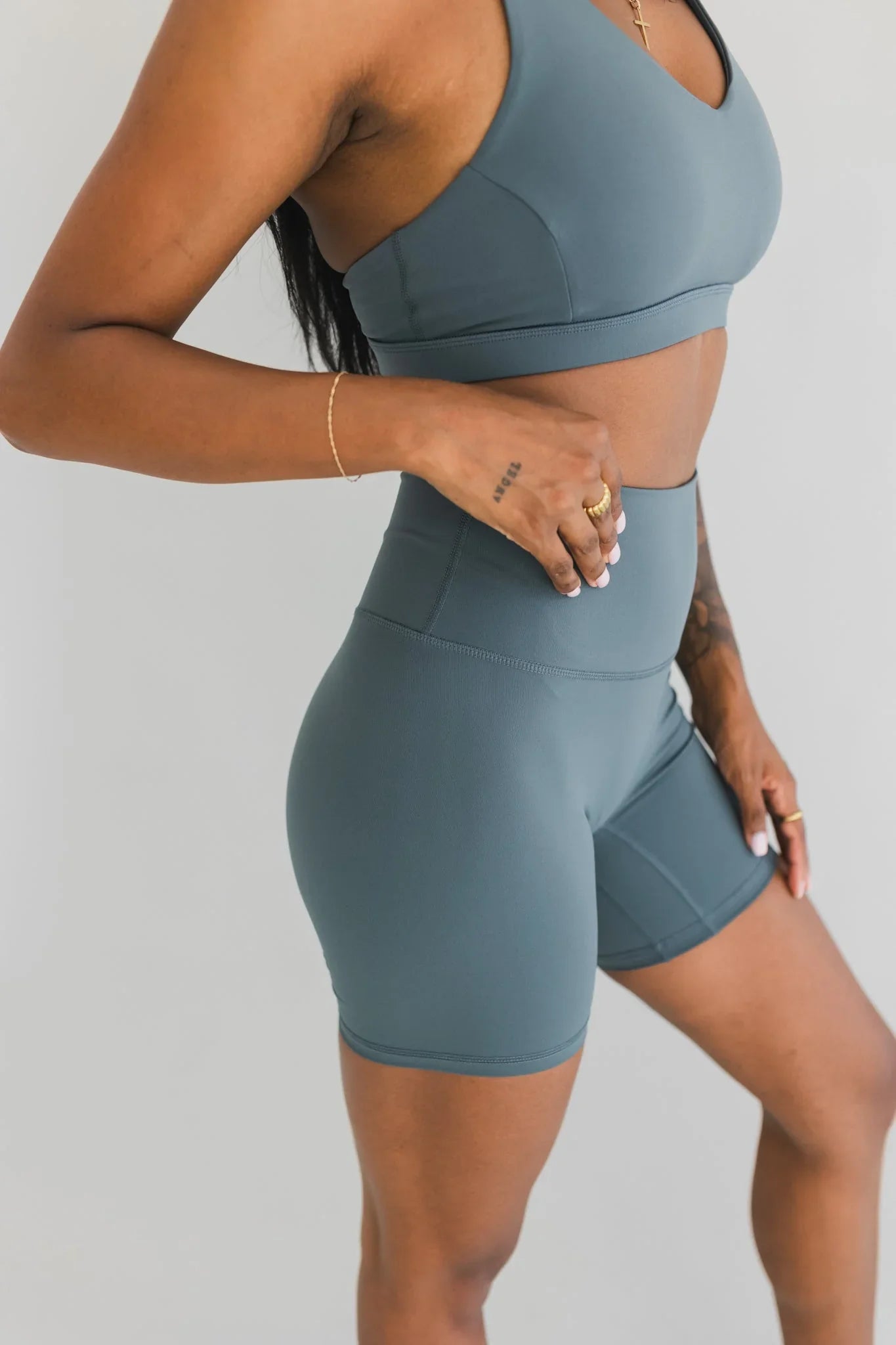 Woman wearing teal sports bra and high-waisted biker shorts, athletic activewear set