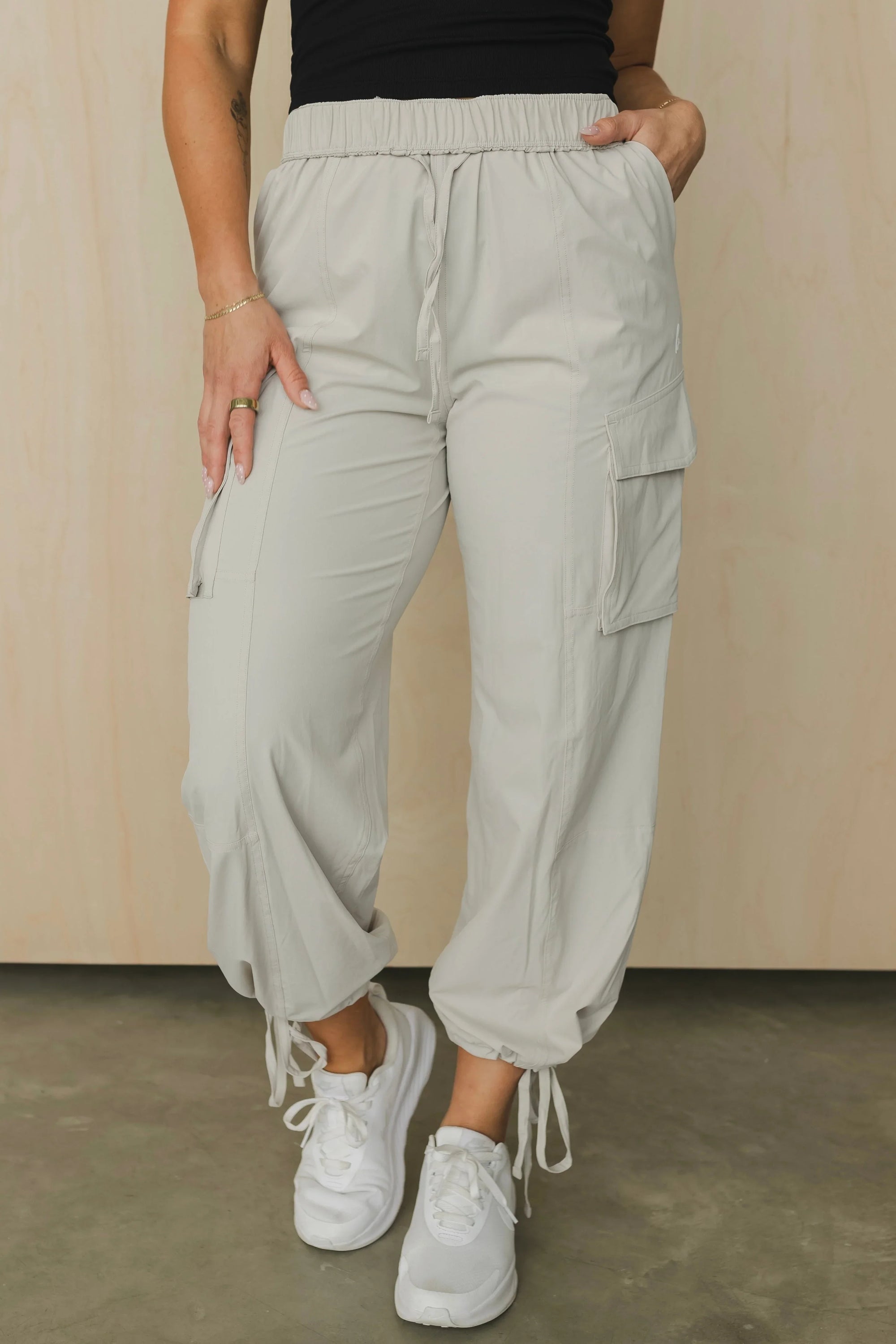 Beige cargo jogger pants with drawstring waist and ankles, styled with white sneakers