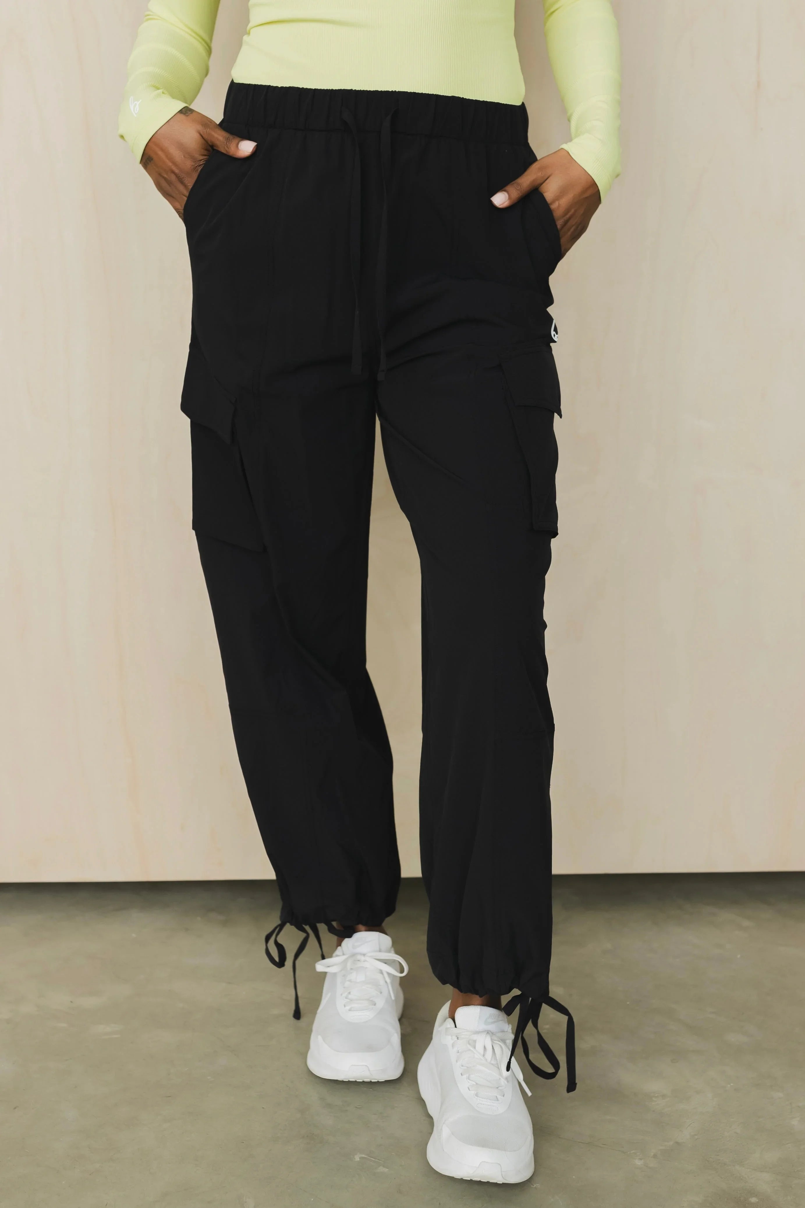 Woman wearing black cargo jogger pants with drawstring cuffs and white sneakers