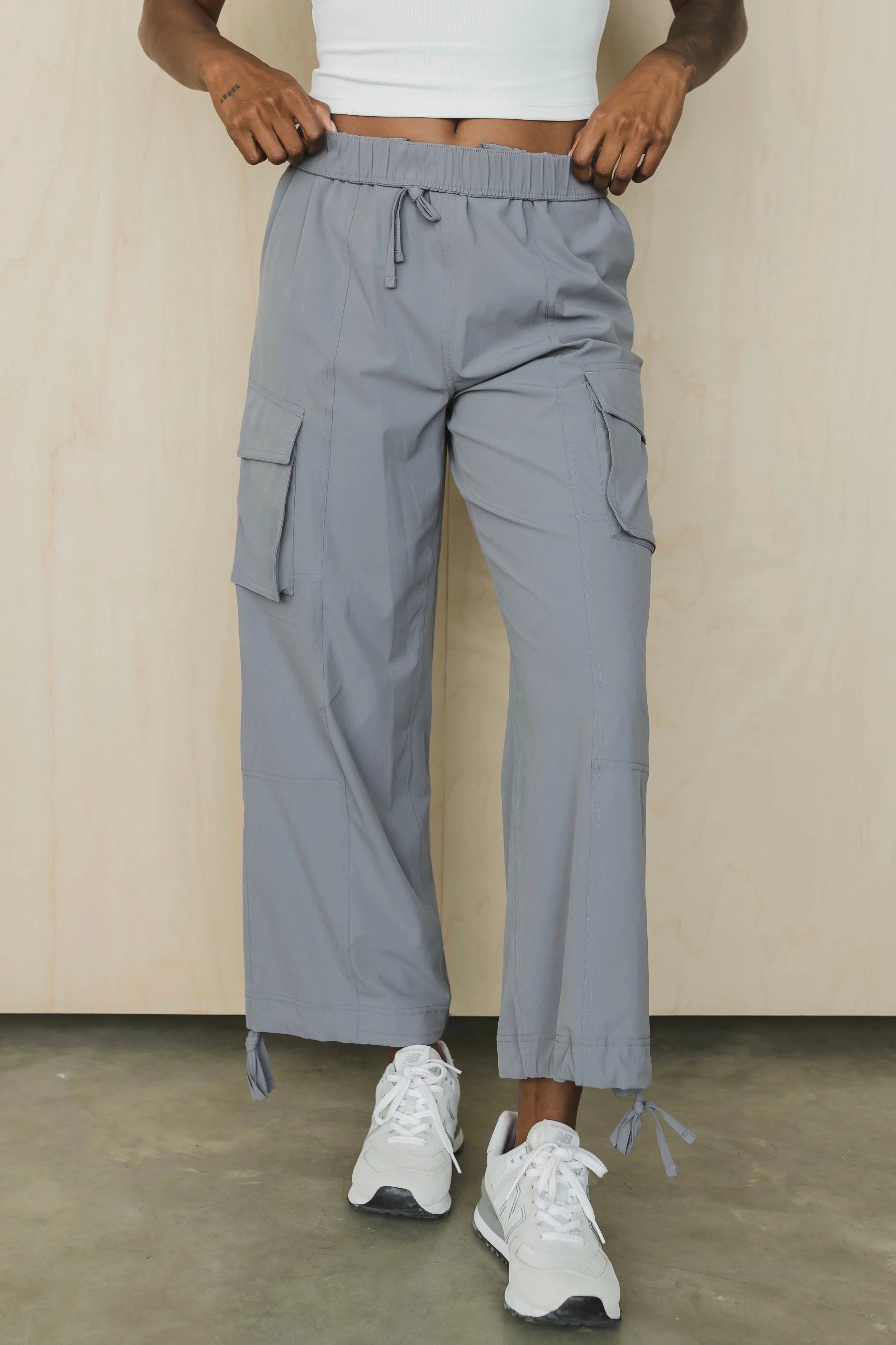 Gray cargo pants with drawstring waist and pockets, styled with white sneakers