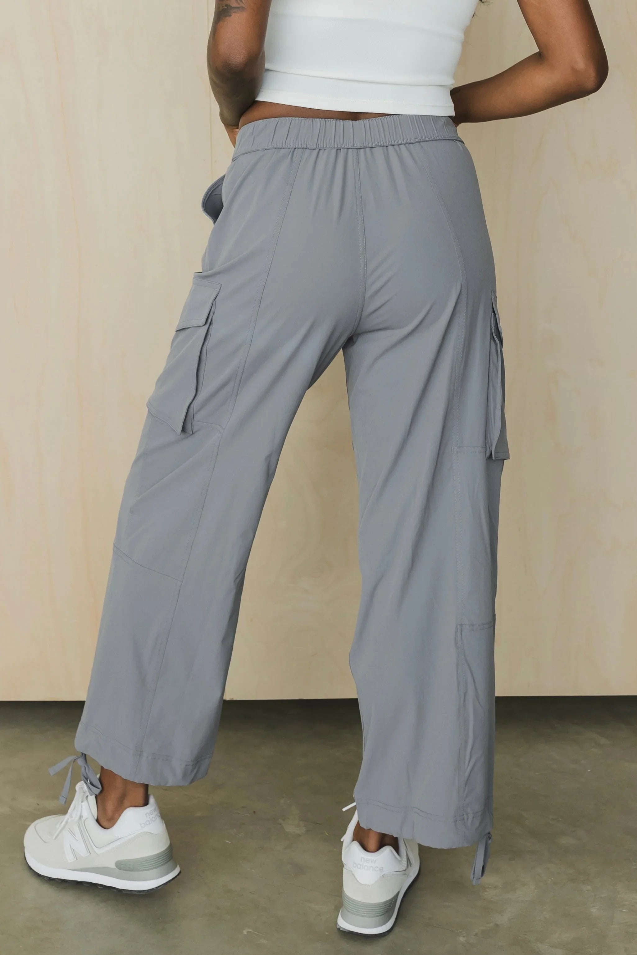 Woman in gray cargo pants and white sneakers, cropped white top, standing indoors